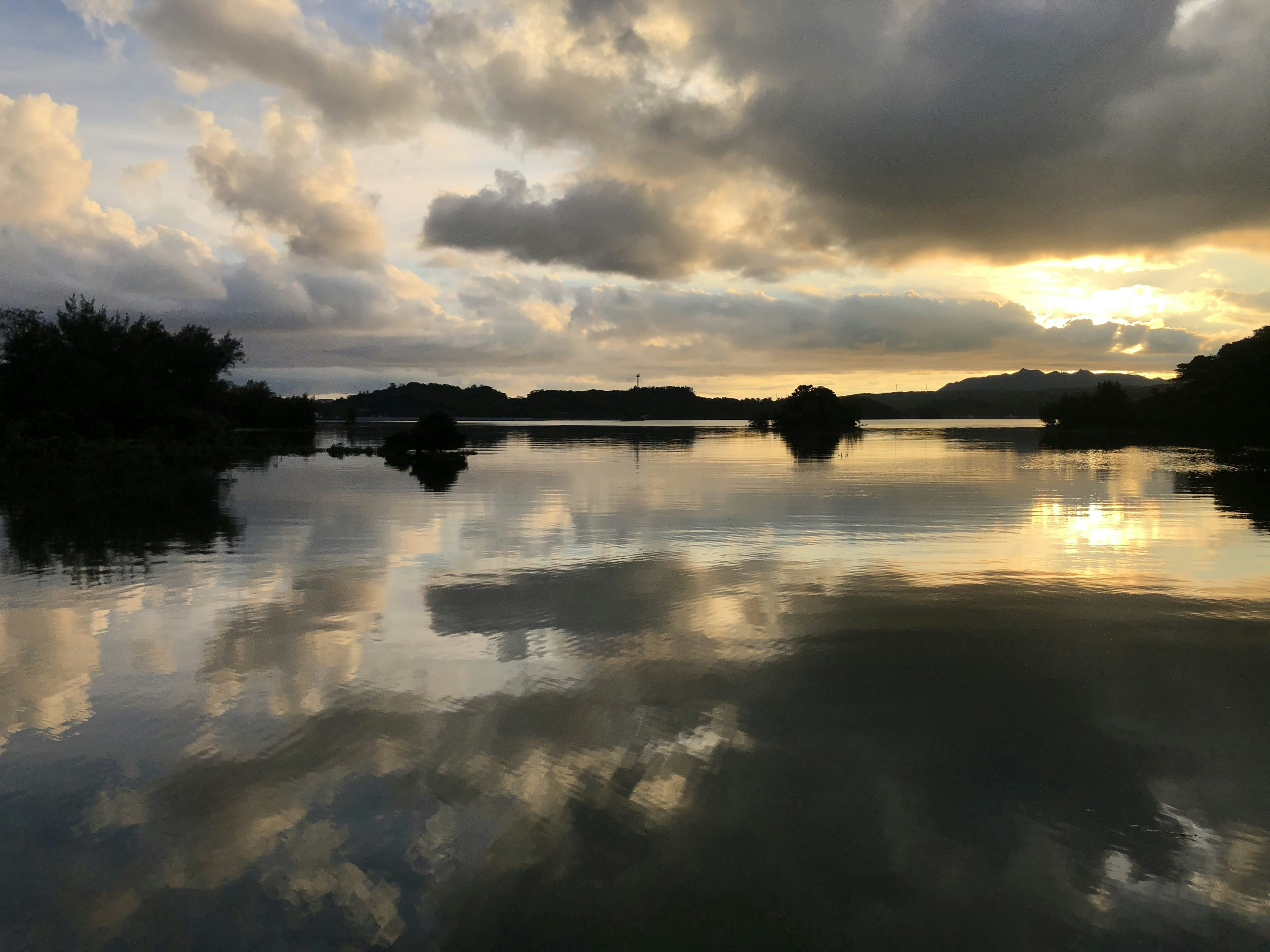 静かな湖面に映る雲と夕日、穏やかな風景