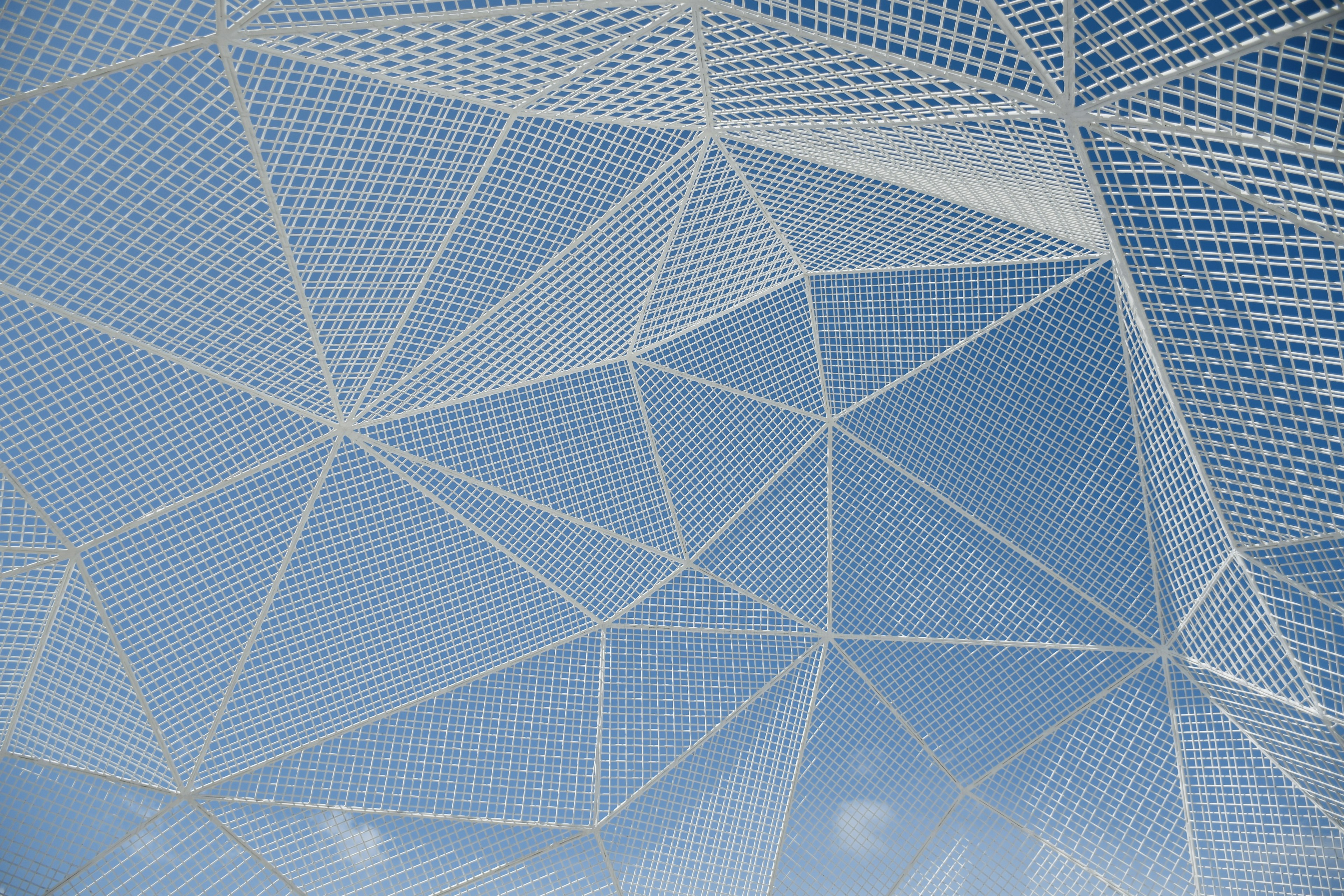 Geometric white mesh structure against a blue sky