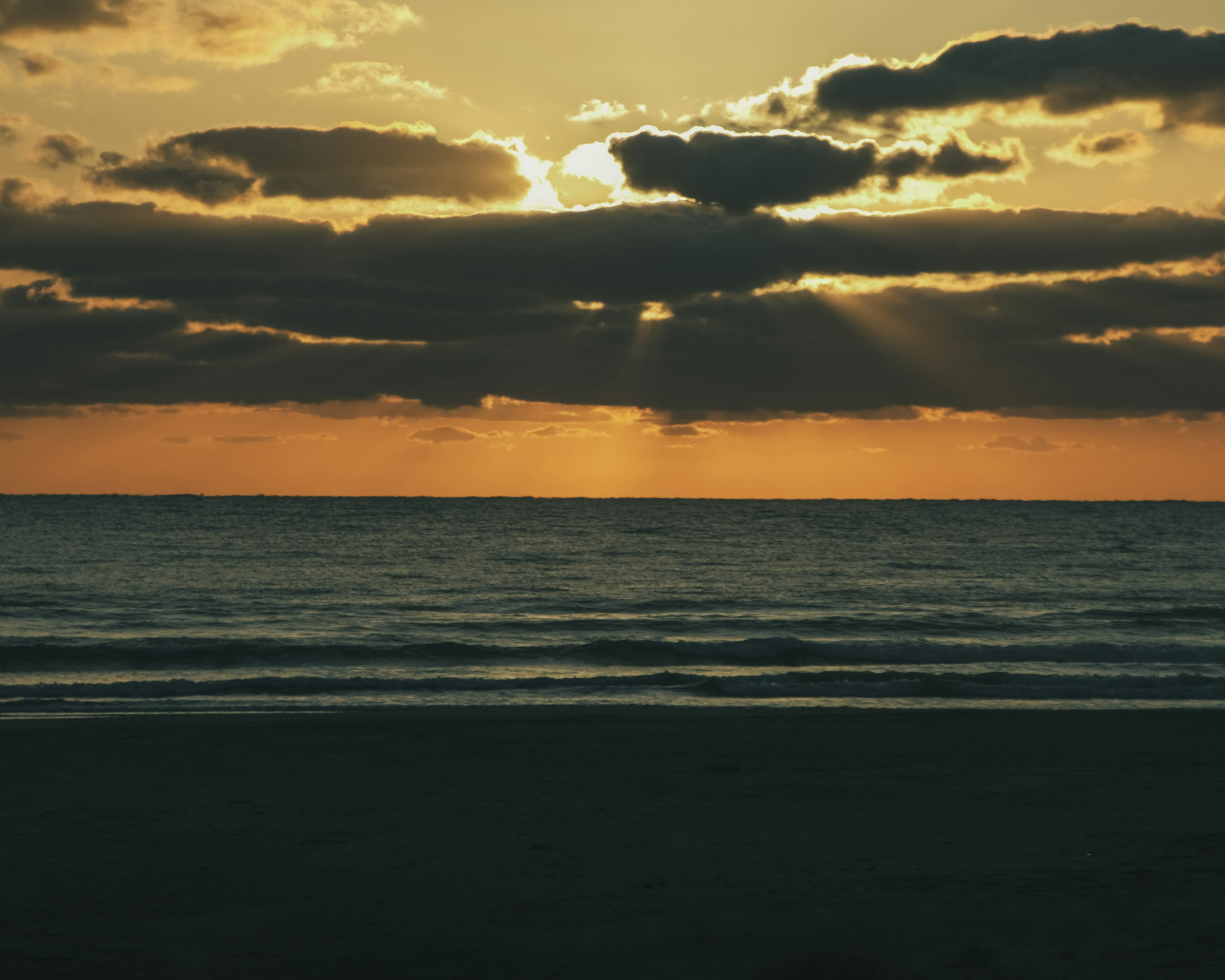 Senja di atas laut dengan awan dan sinar cahaya