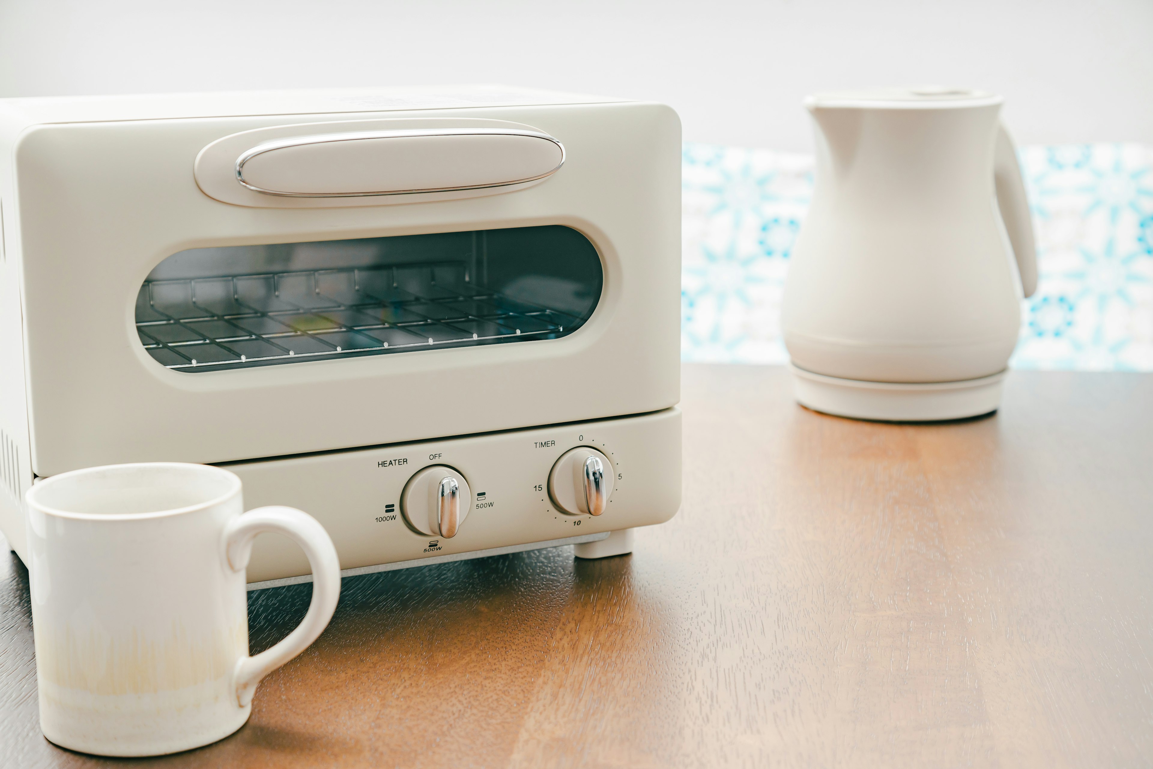 White toaster and white pitcher on a table with a coffee cup