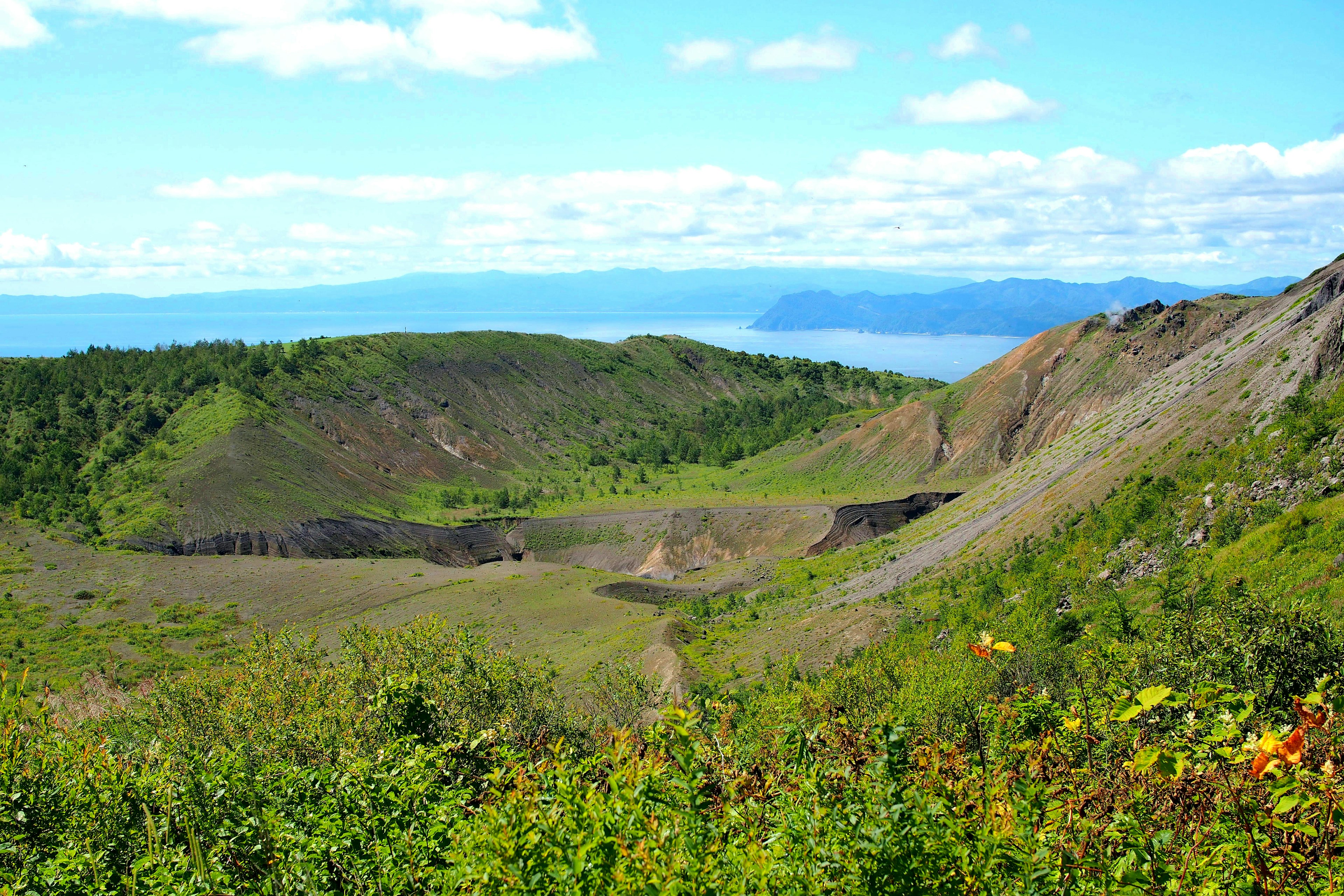 Vue panoramique d'un cratère volcanique entouré de verdure luxuriante