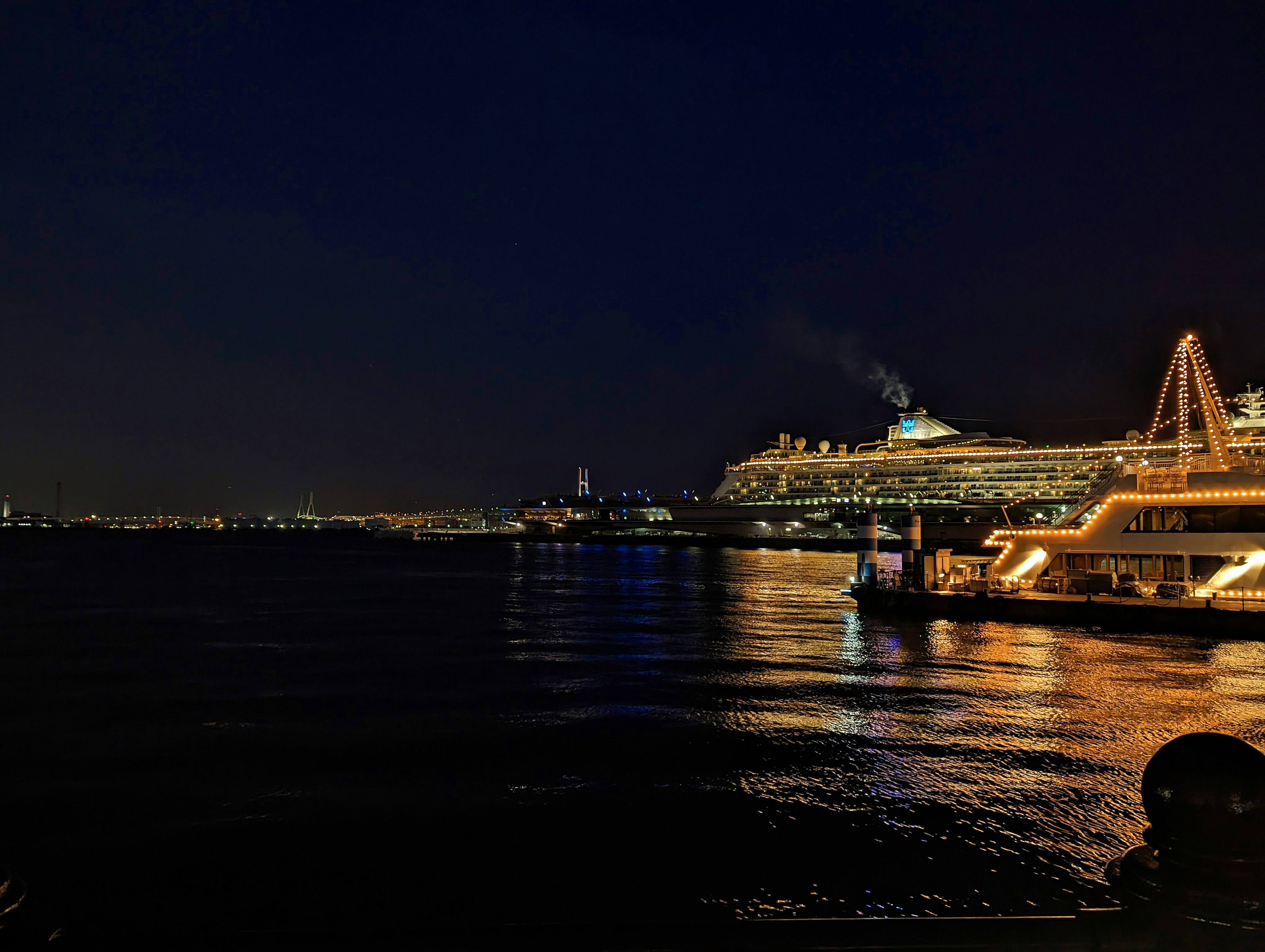 Luxuskreuzfahrtschiff nachts beleuchtet und auf dem Wasser reflektiert