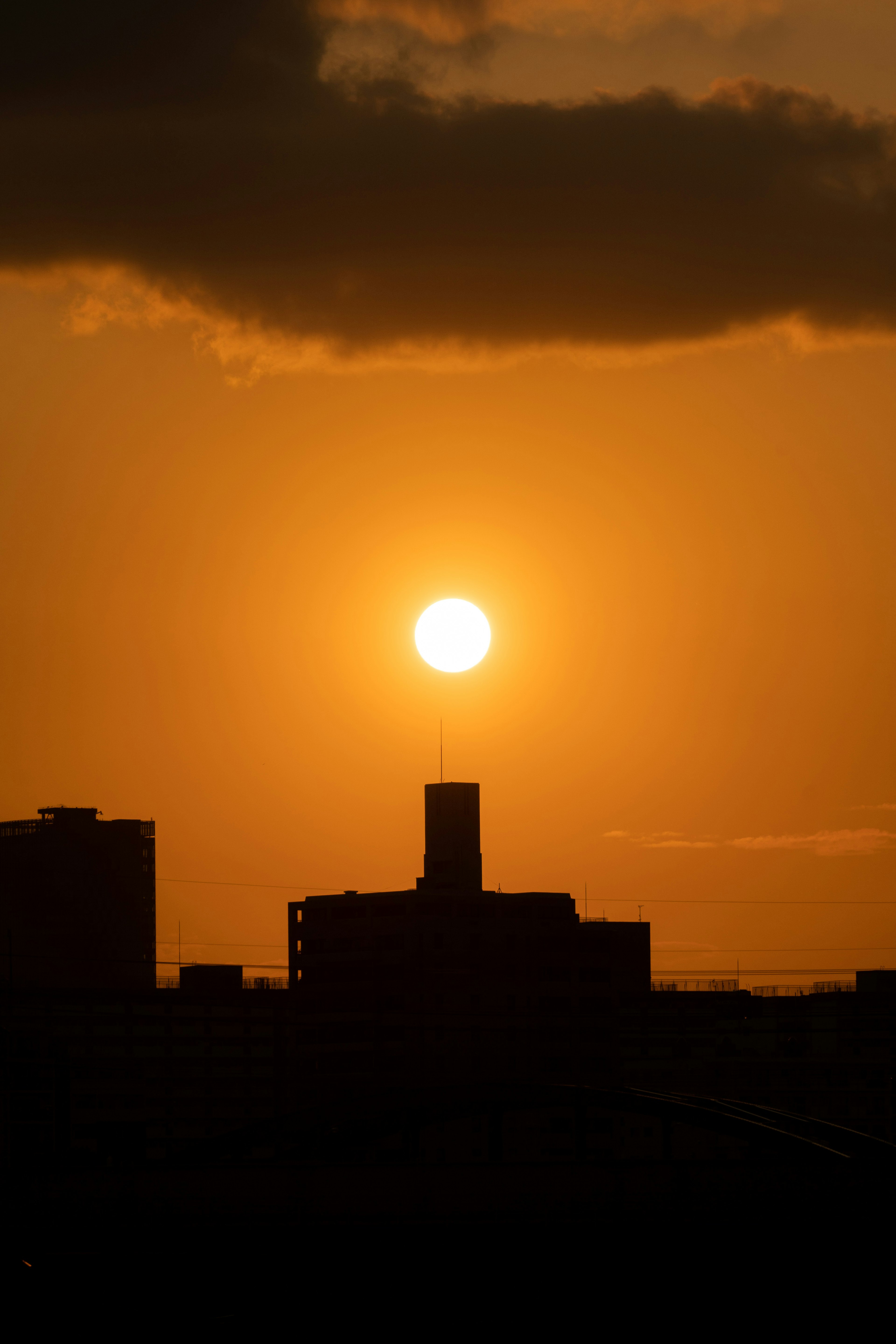 夕日がビルのシルエットの後ろに沈む風景