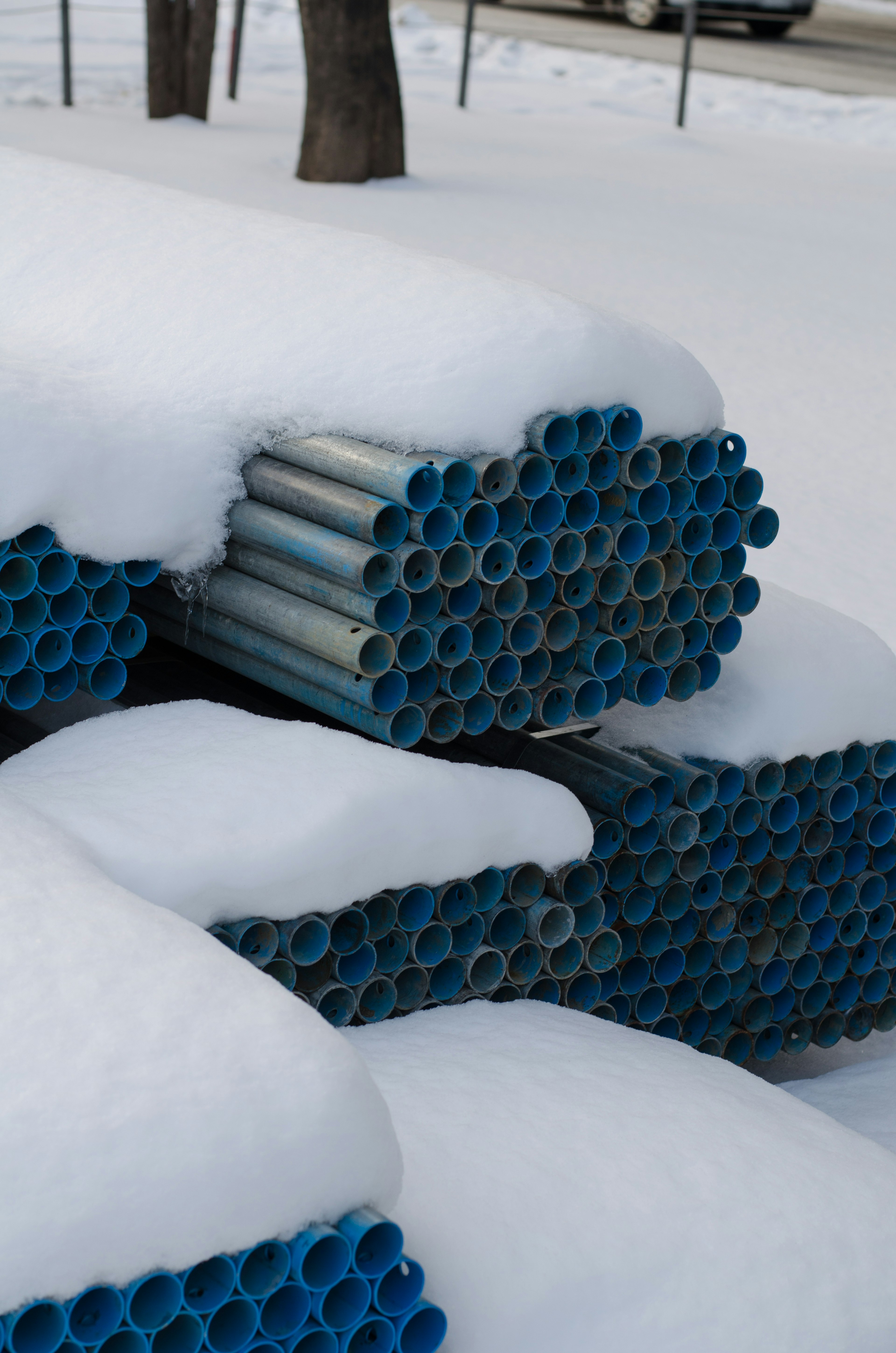 Stack of blue pipes covered in snow