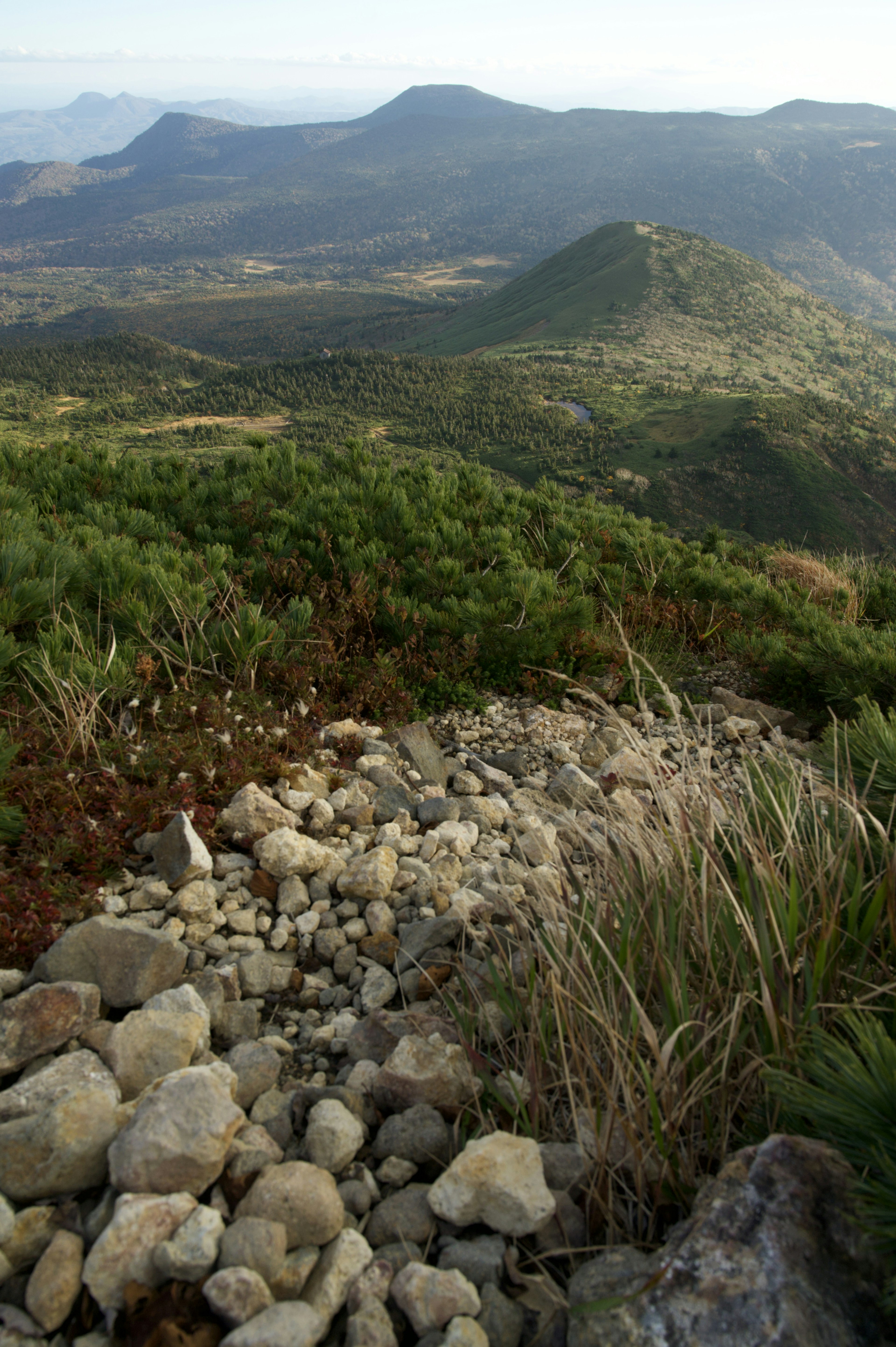 Vista escénica de montañas con un camino rocoso y vegetación exuberante