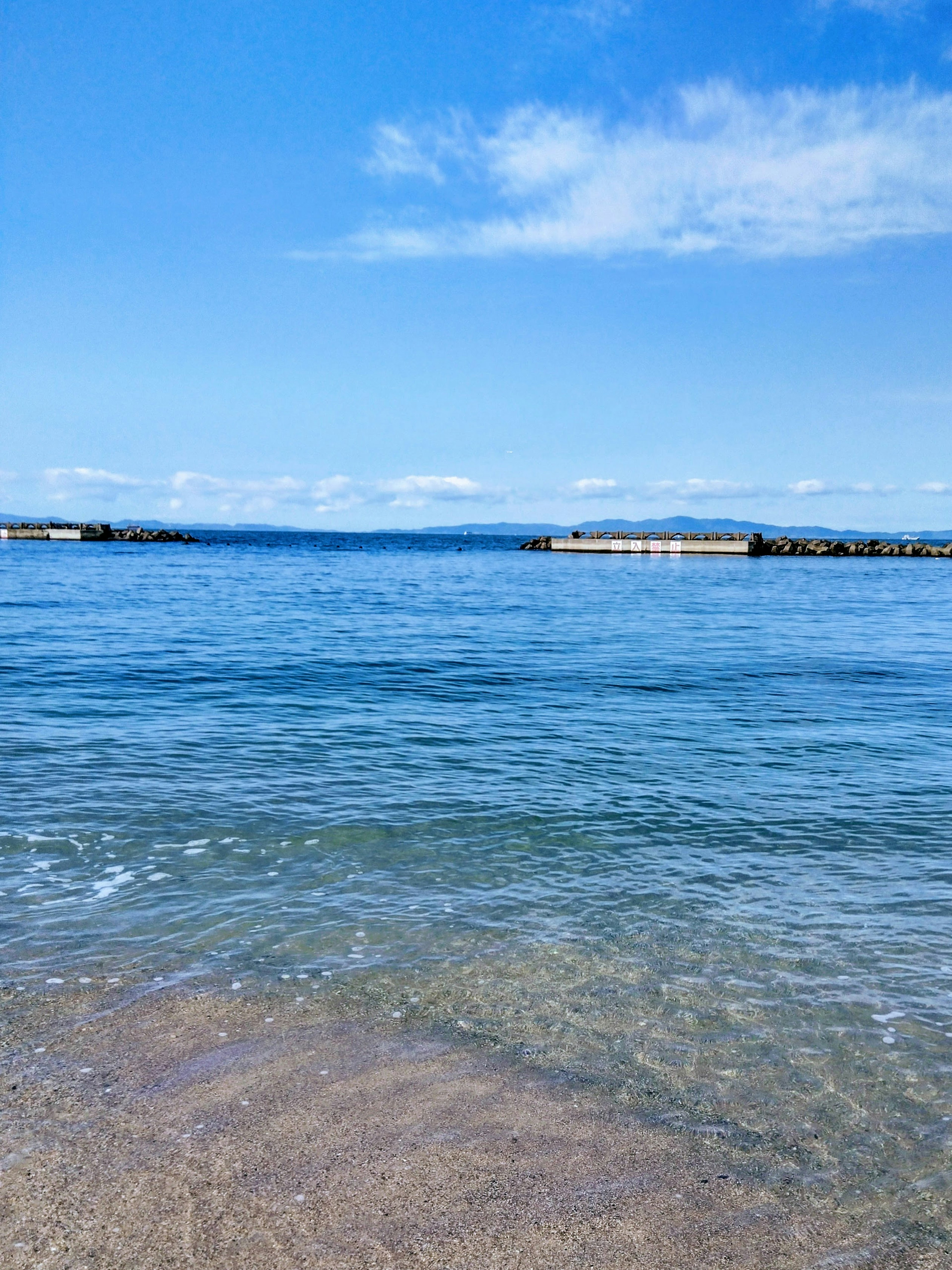 Eine ruhige Aussicht auf den blauen Ozean und den klaren Himmel sanfte Wellen schlagen an den Sandstrand