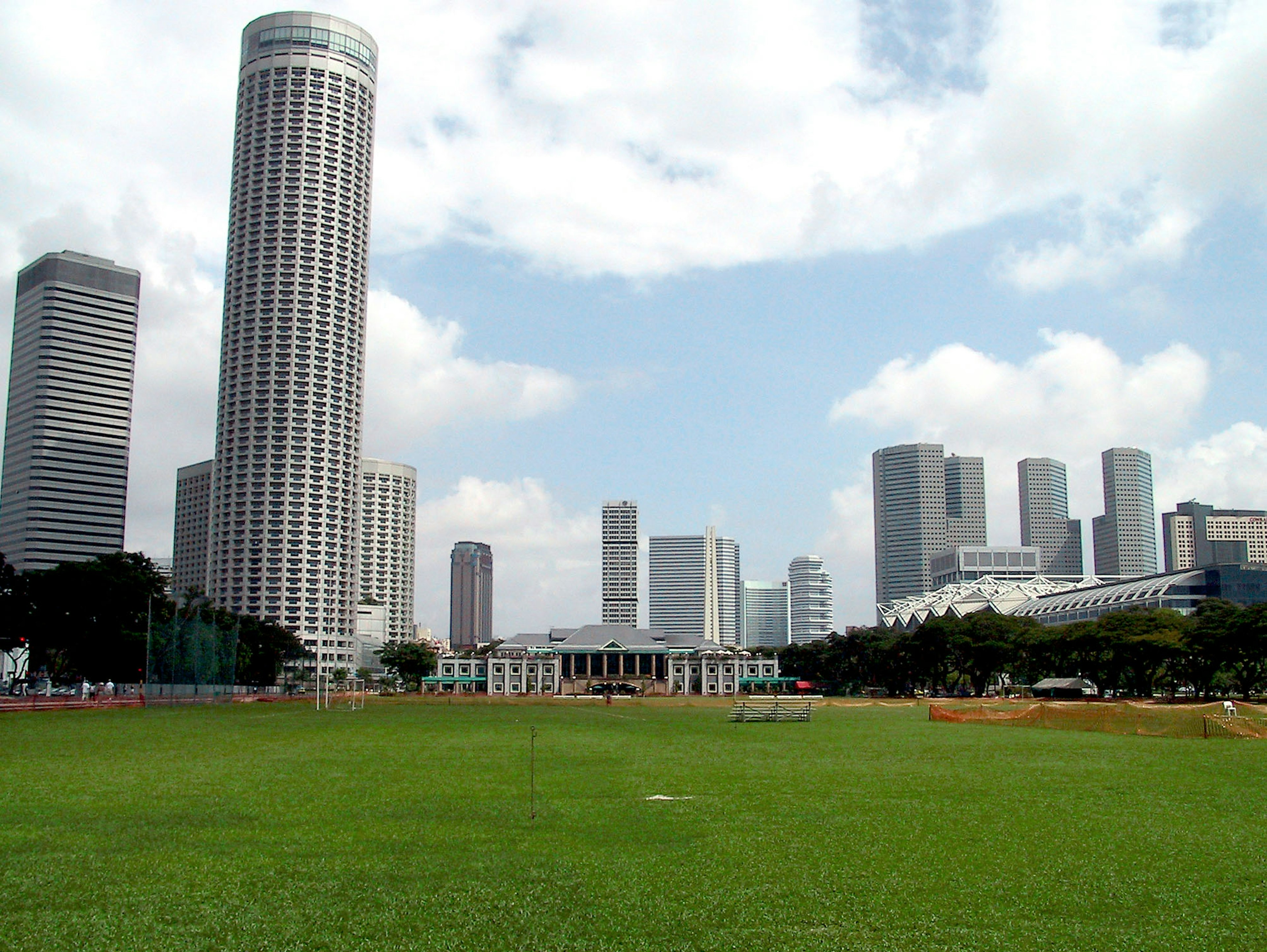 Taman hijau dengan gedung pencakar langit dan langit biru