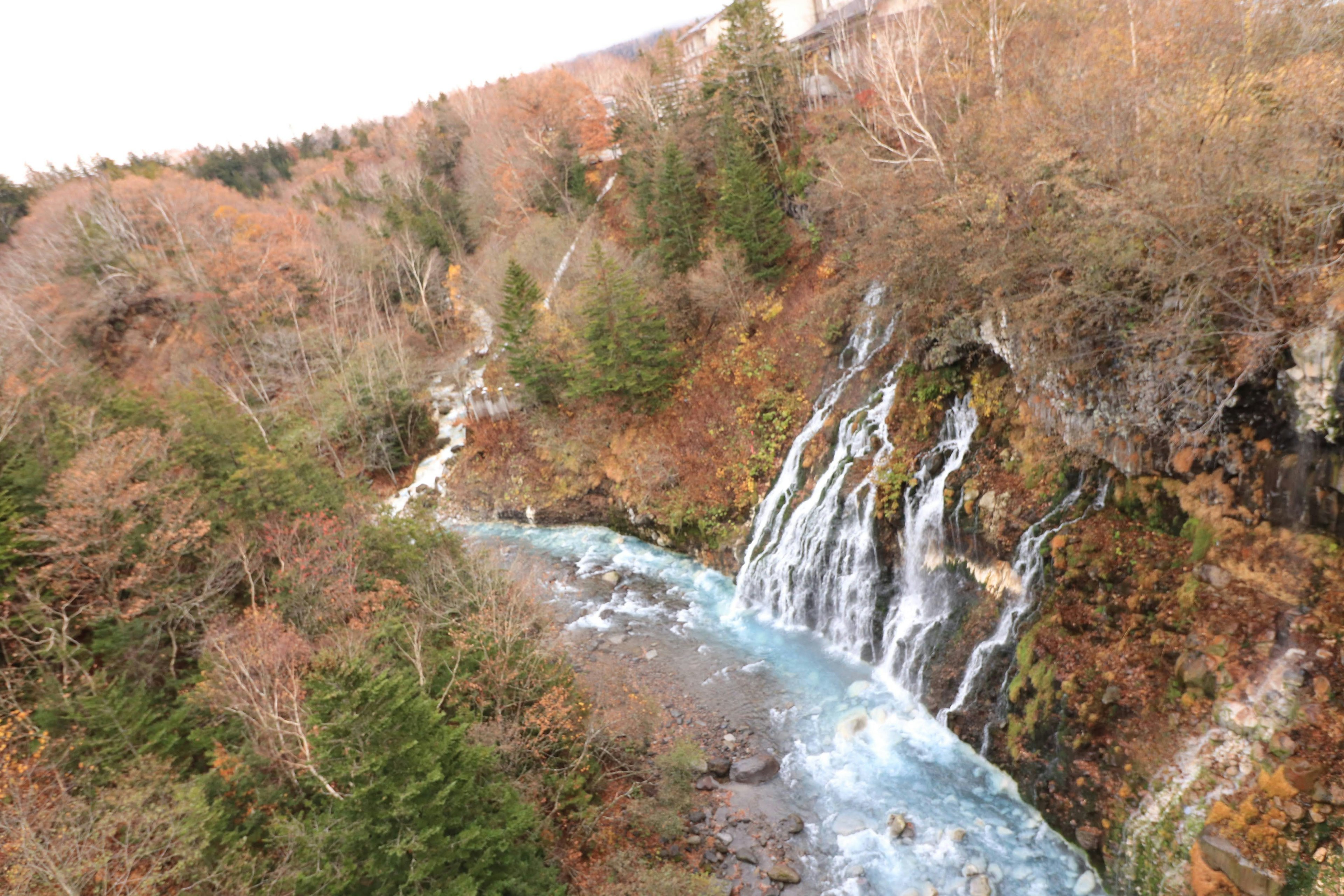 Schöner Wasserfall und blauer Fluss in einer herbstlichen Landschaft