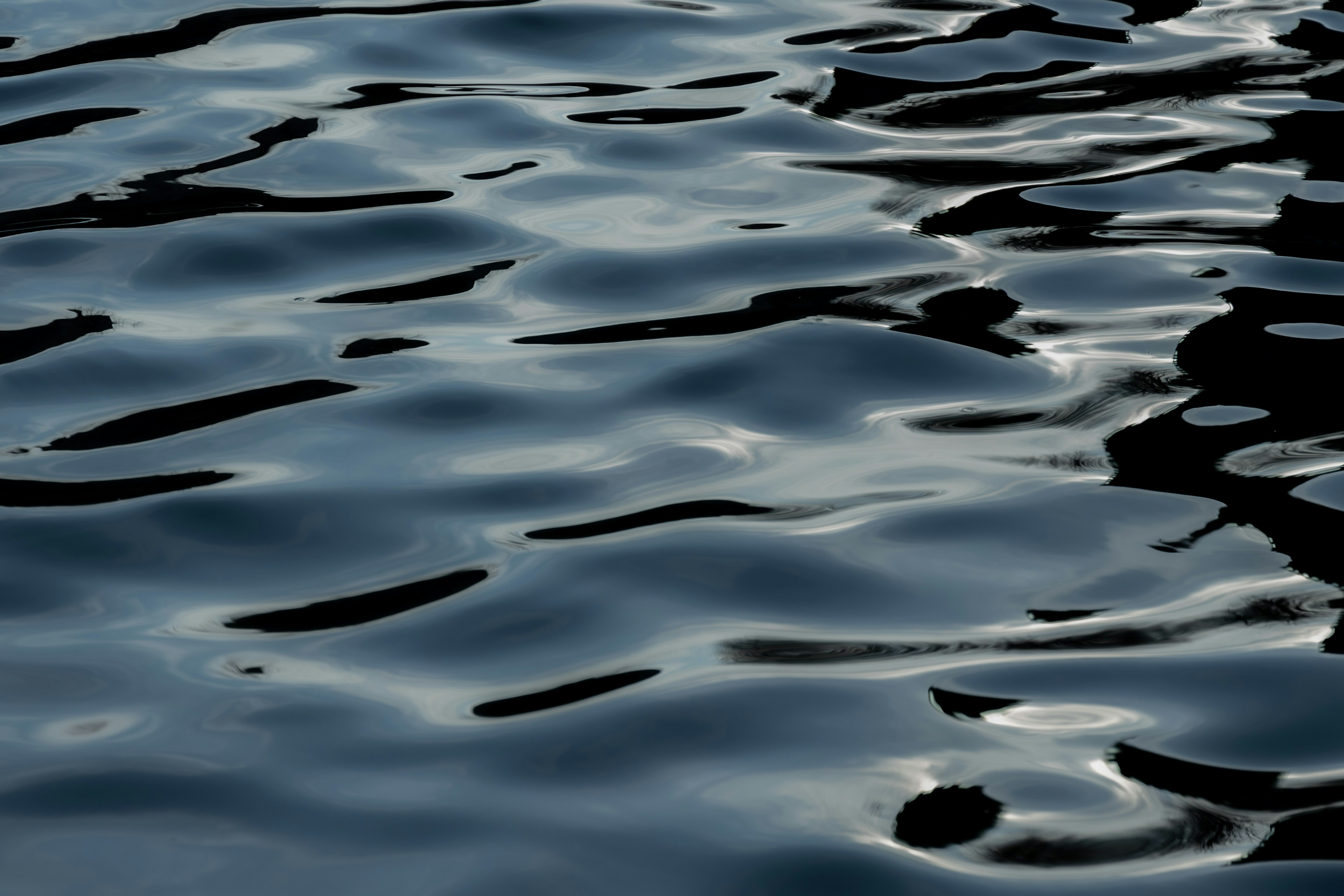 Surface d'eau sombre avec des ondulations douces et des reflets