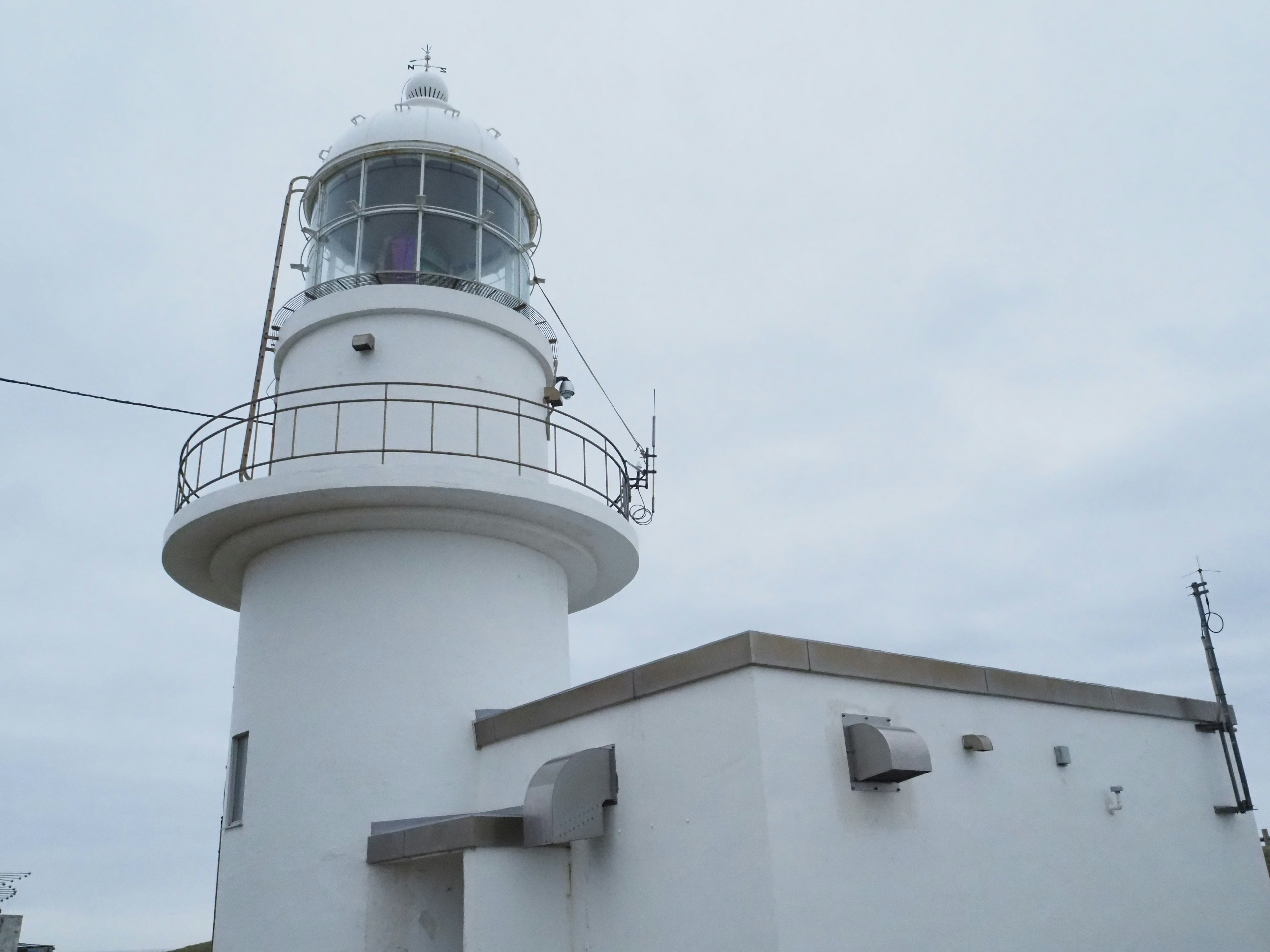 A white lighthouse stands under a cloudy sky