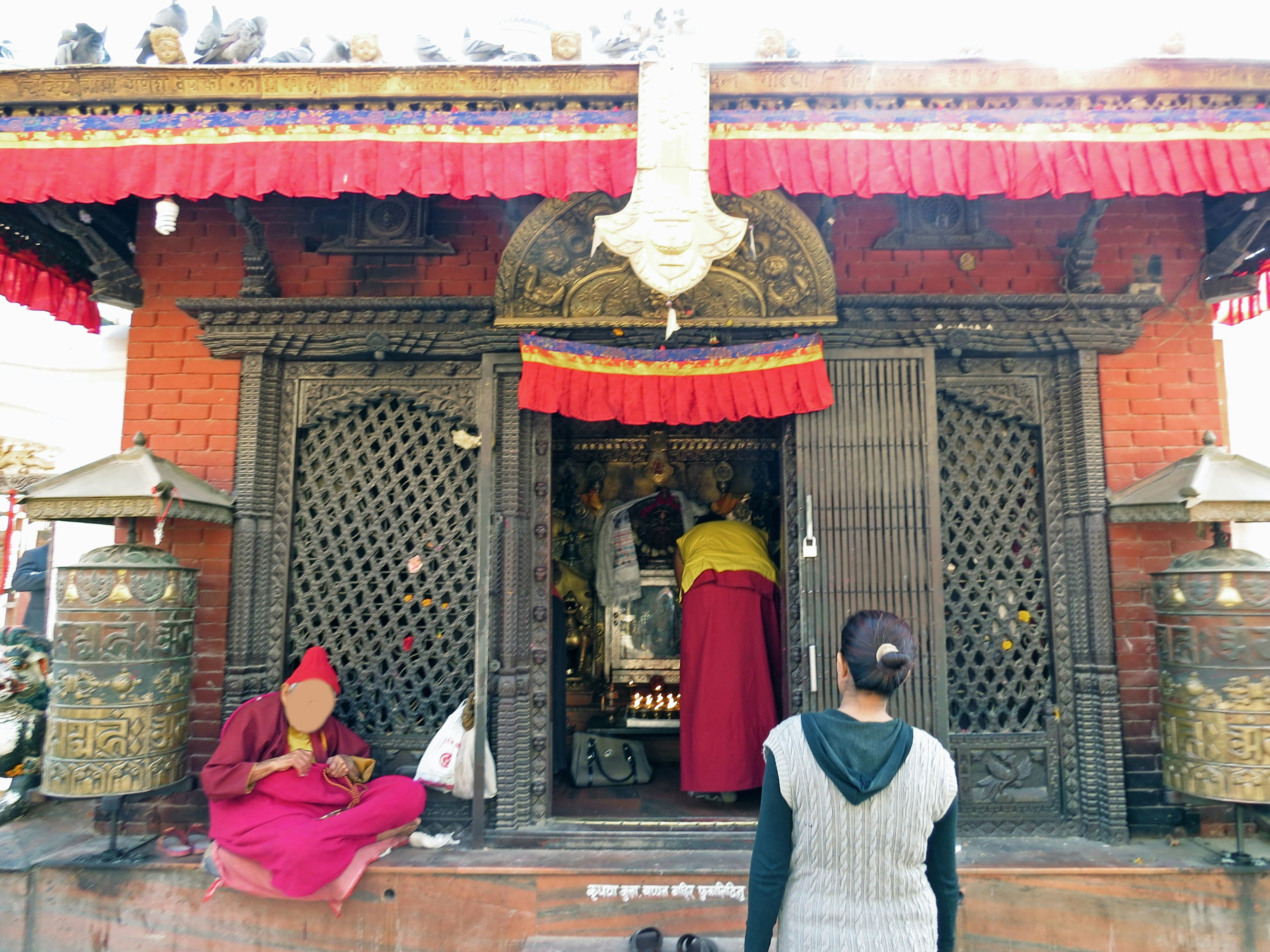 寺庙入口处有红色装饰和祈祷的人