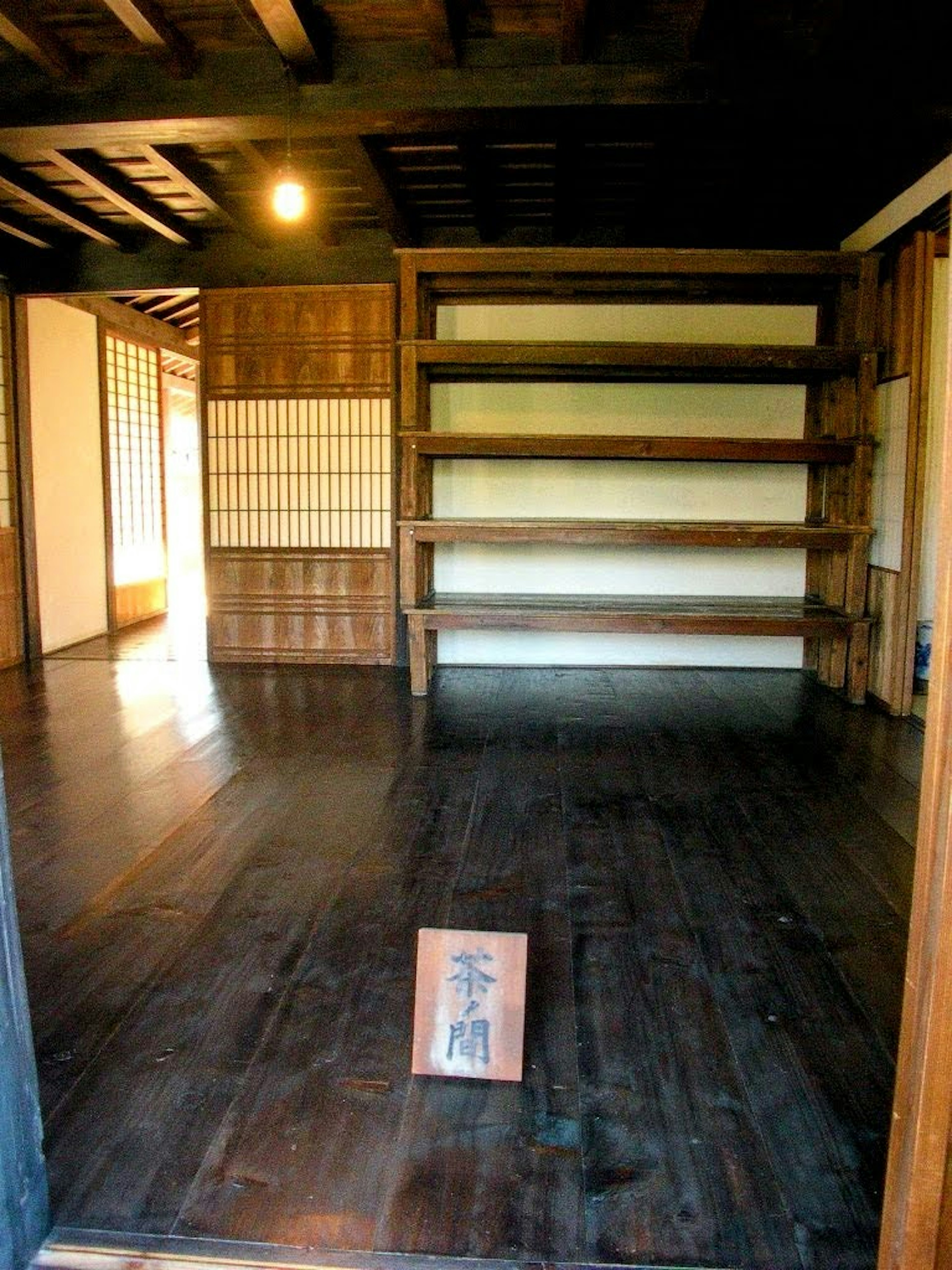 Interior of a traditional Japanese room with wooden shelves and flooring bright lighting visible entrance