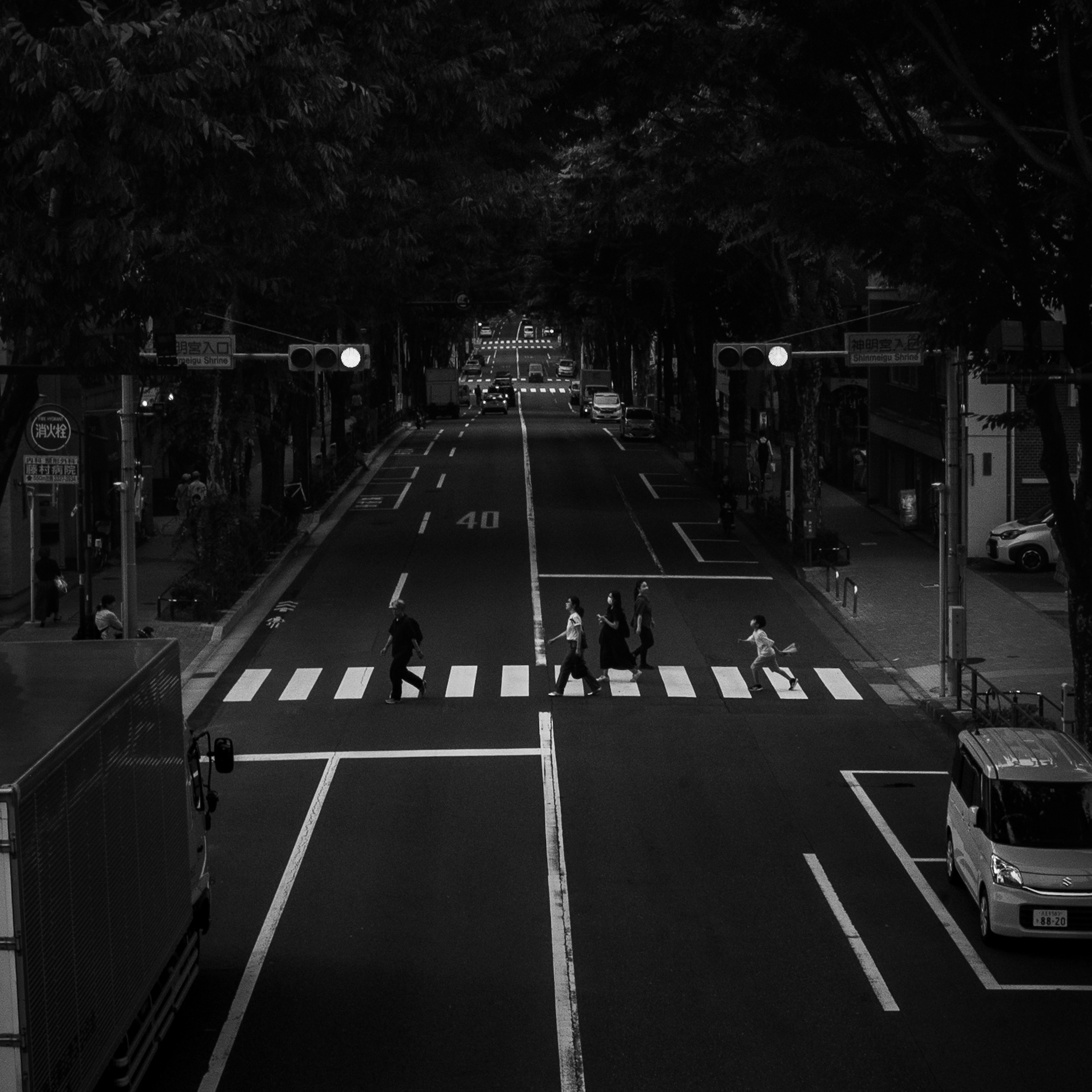 Black and white city intersection with pedestrians crossing the crosswalk