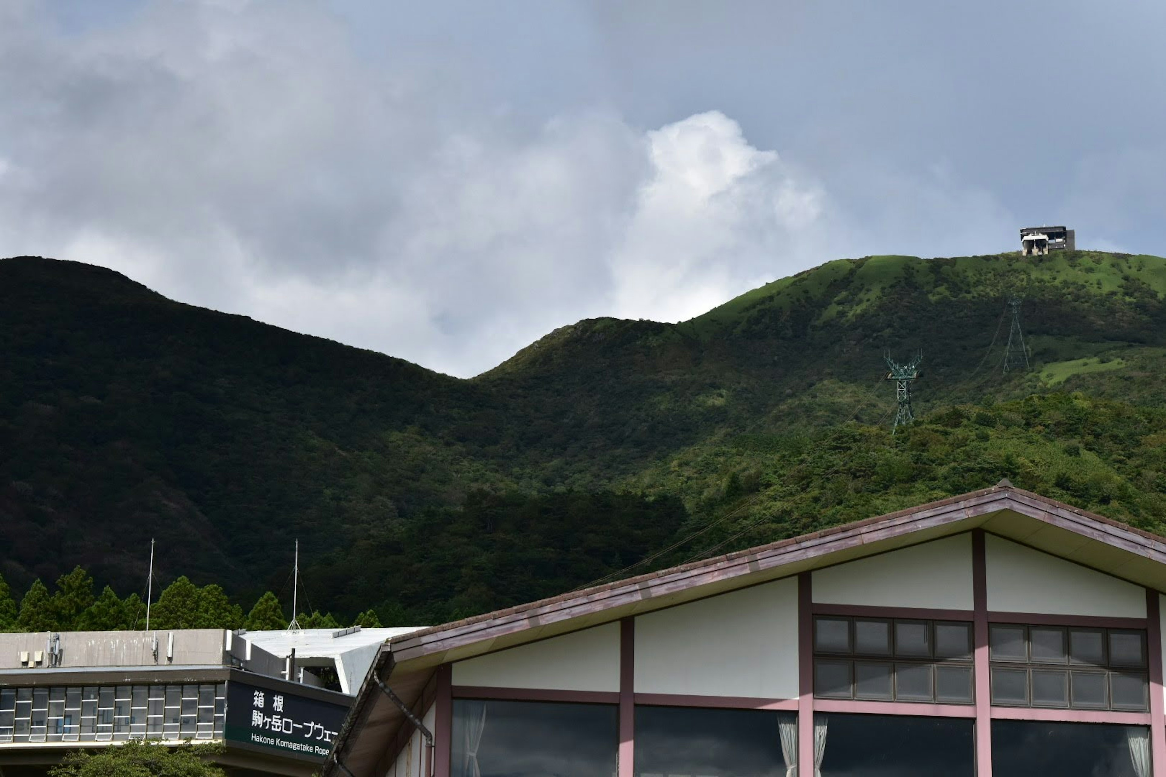 山と小屋の風景 緑豊かな山と雲のある青空