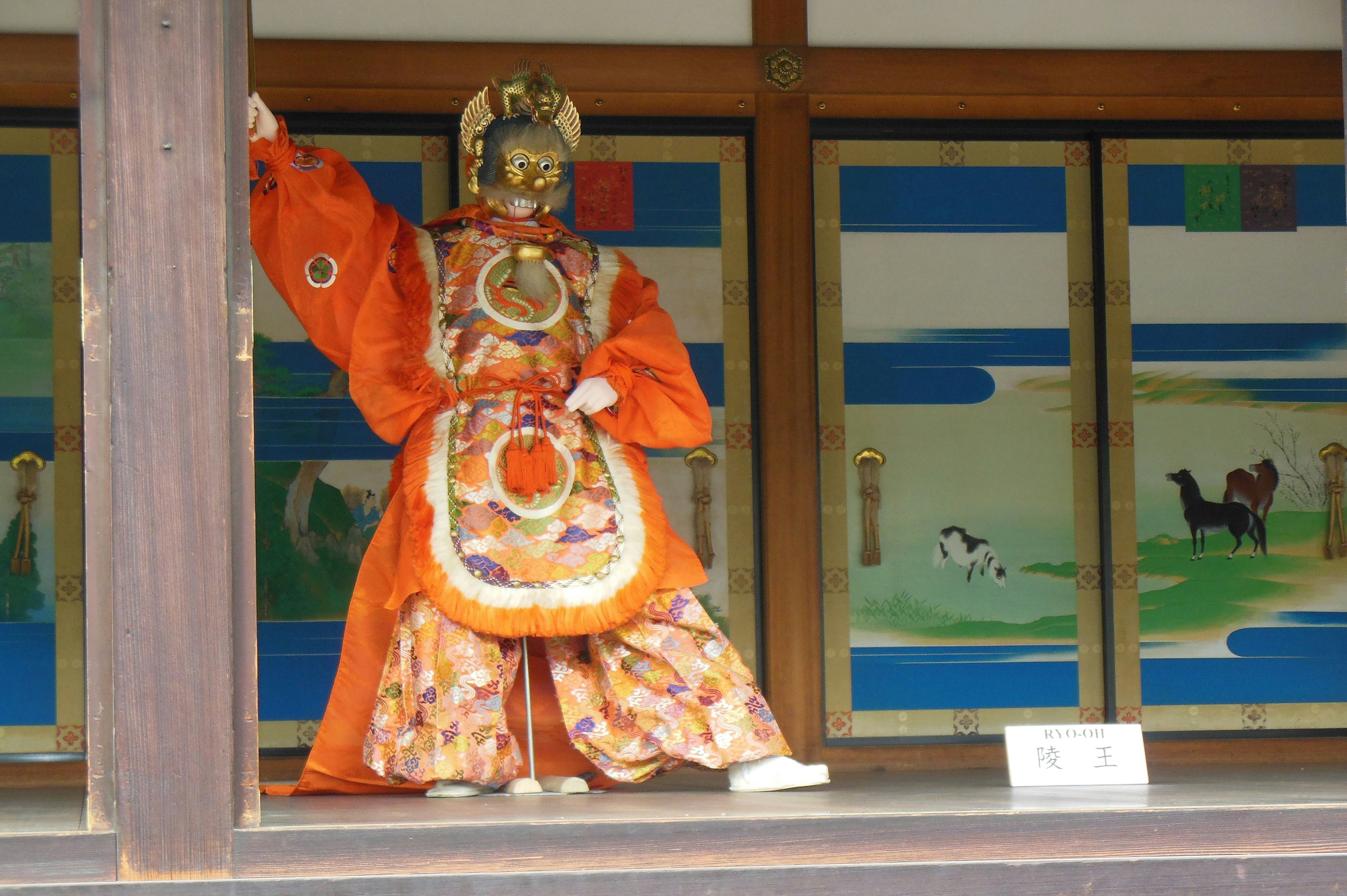 Traditionelle Puppe im orangefarbenen Kostüm, die eine Pose auf der Bühne einnimmt