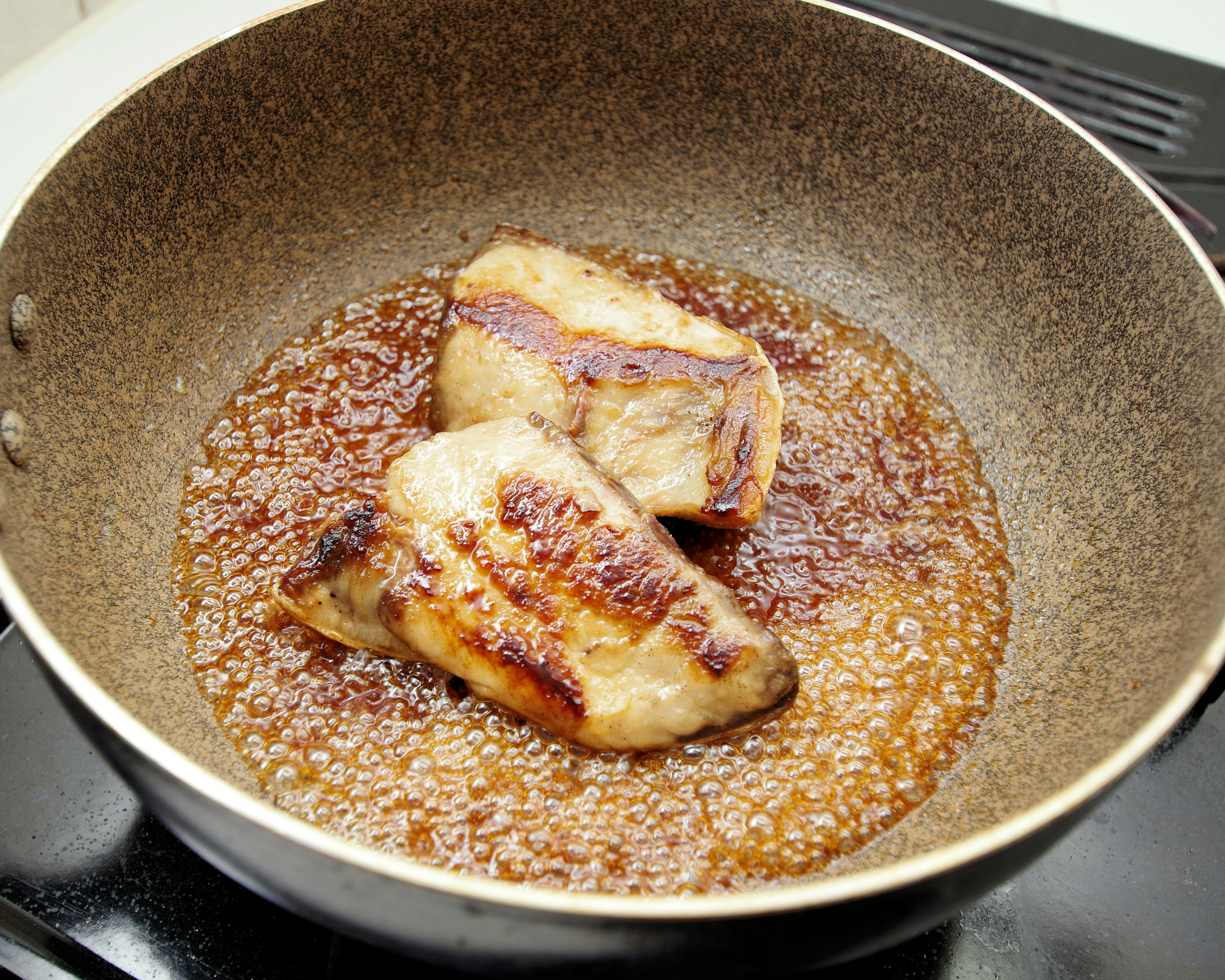 Fish fillets being pan-fried in a skillet