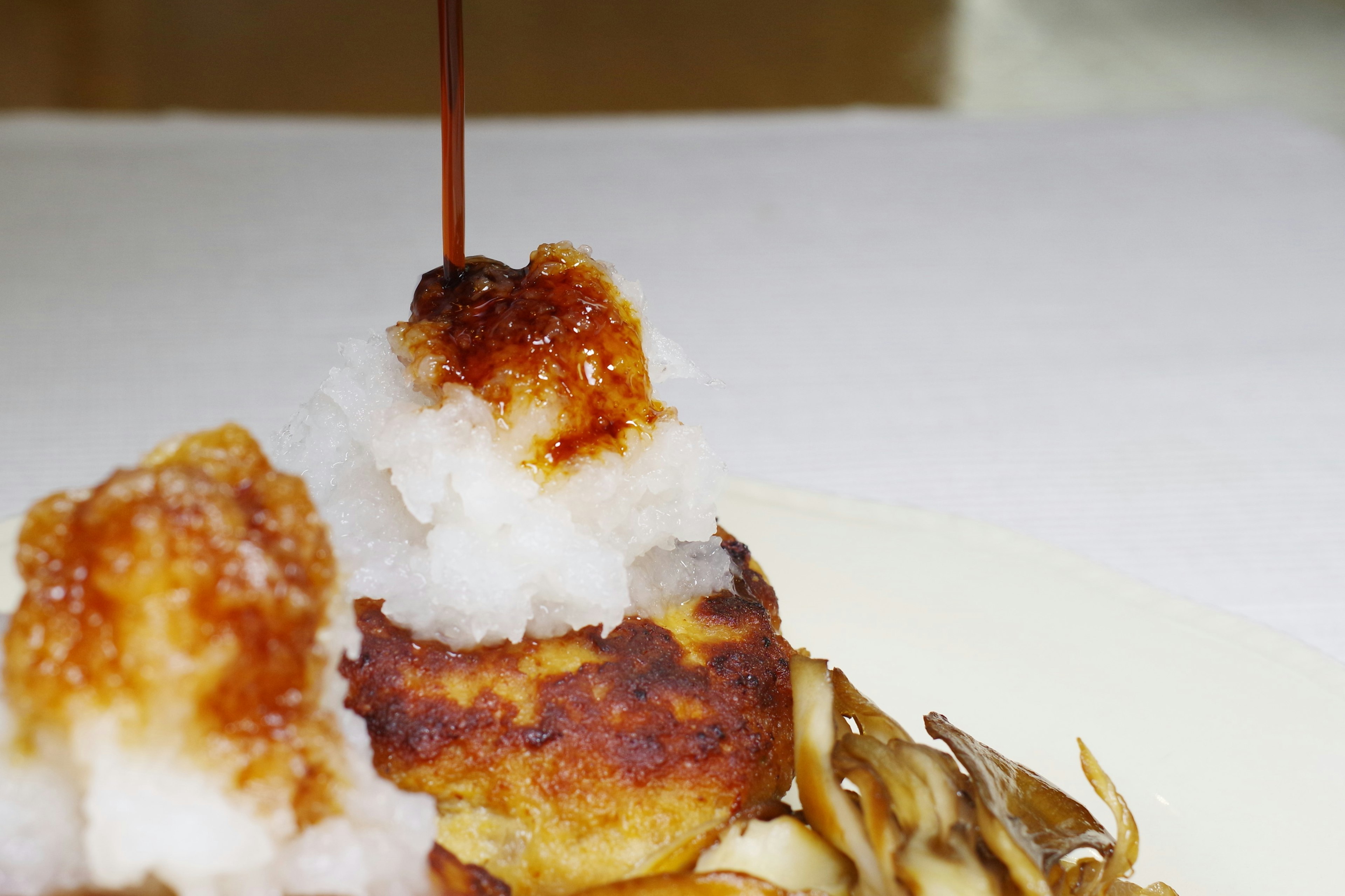 Un plat joliment présenté avec une croquette dorée surmontée d'un sirop sucré et garnie d'une texture ressemblant à de la neige