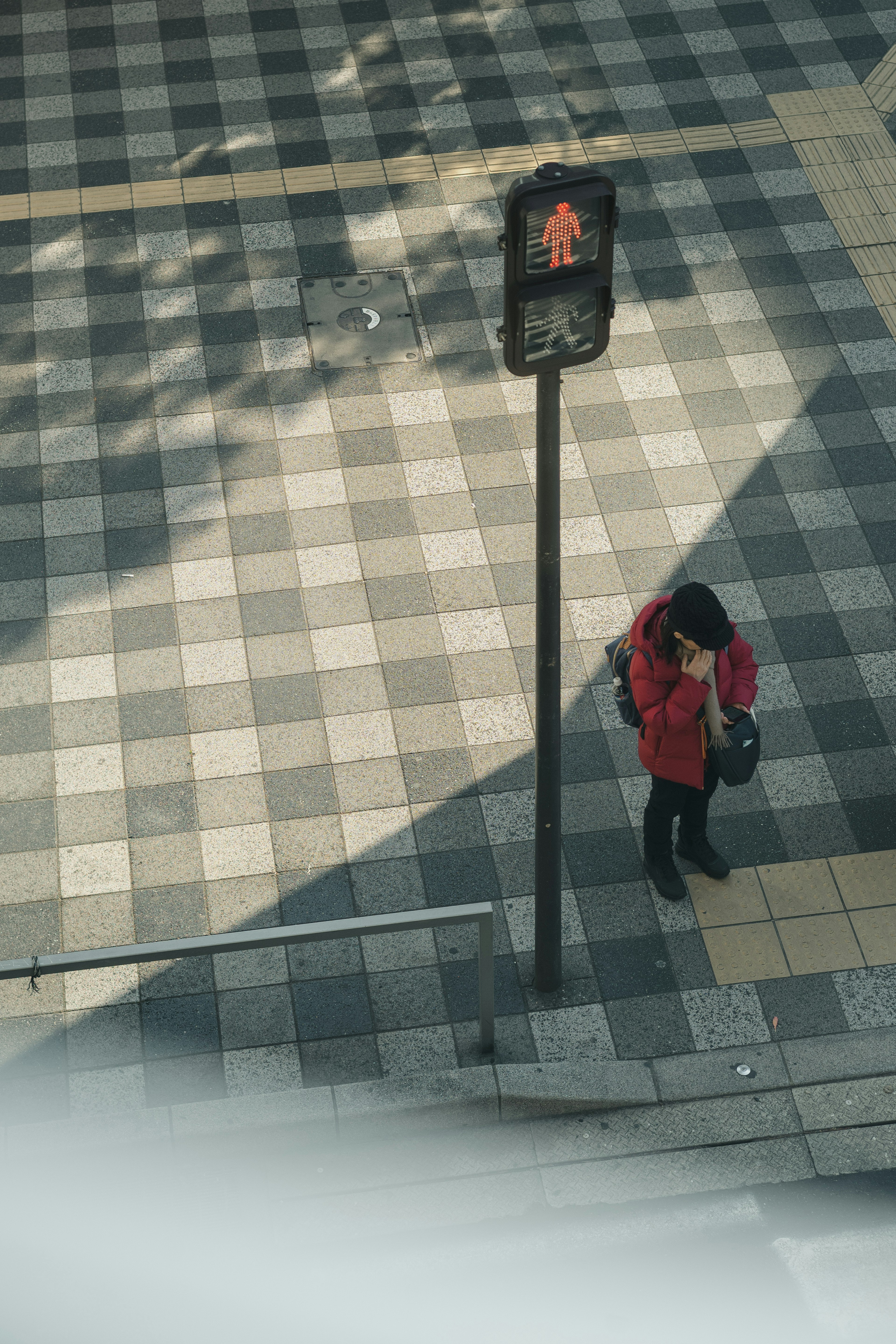 赤いコートを着た人物が歩道に立っている写真