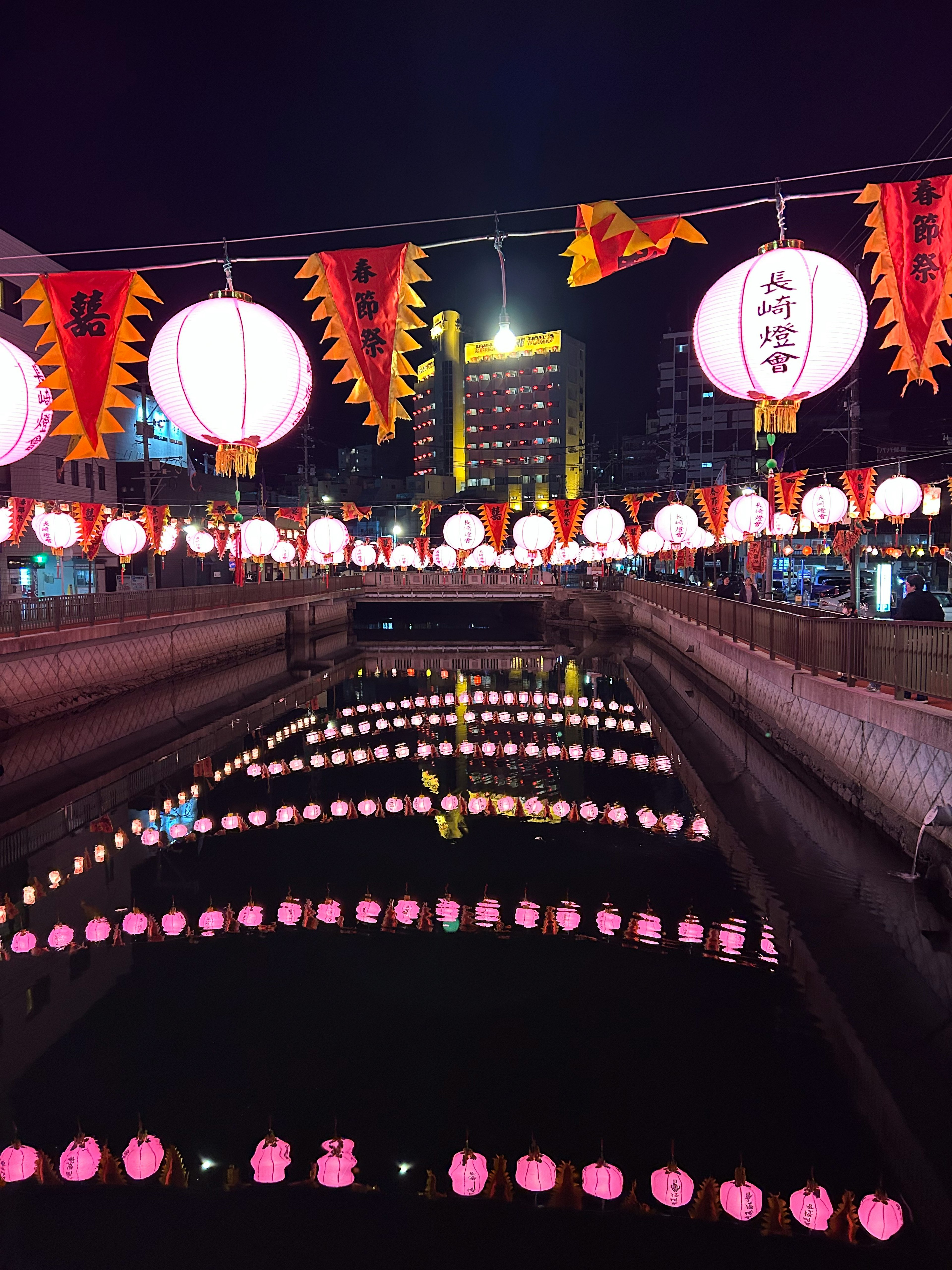 Lanterns floating on a river at night with reflections