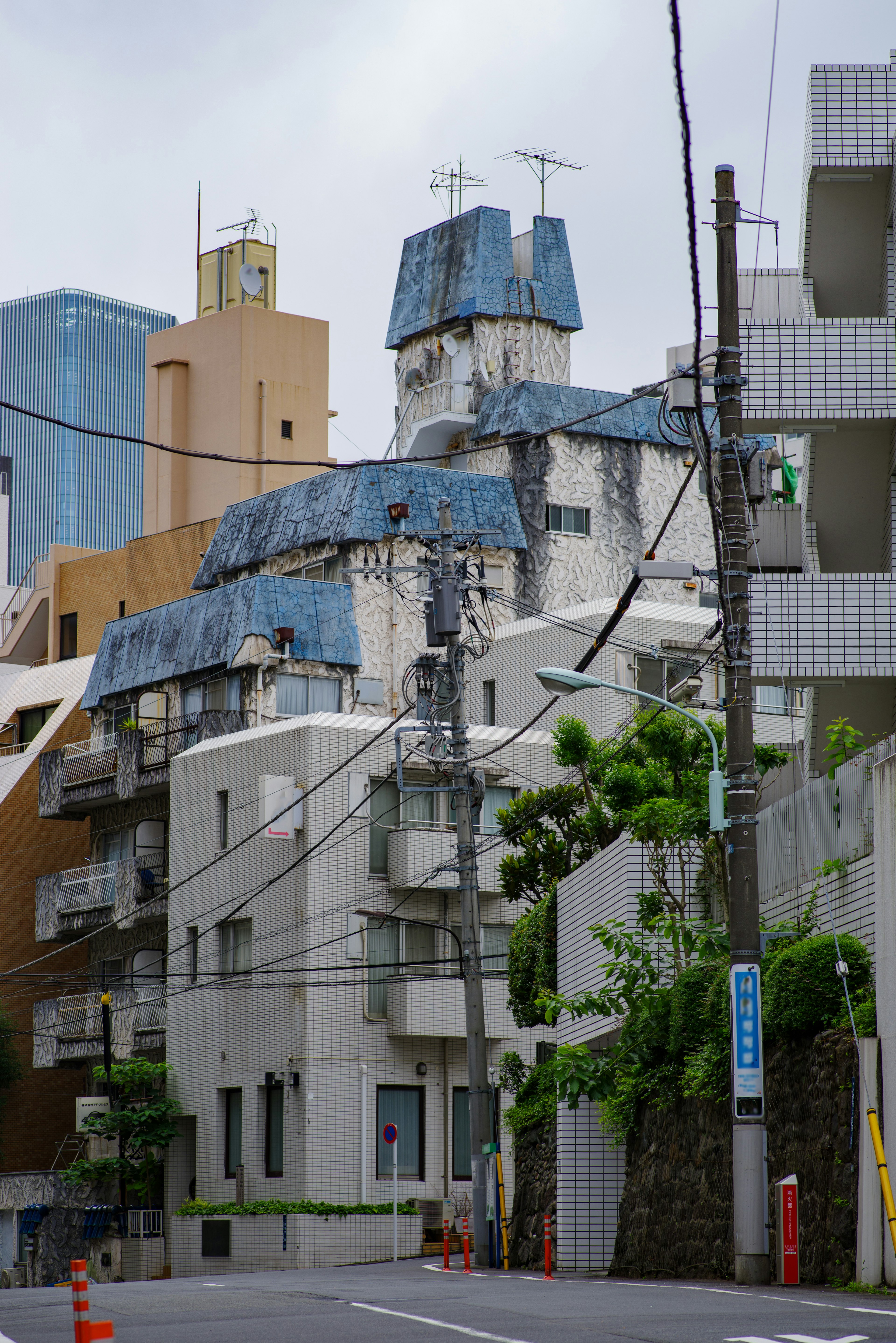 Bâtiment unique avec un toit bleu dans une rue résidentielle