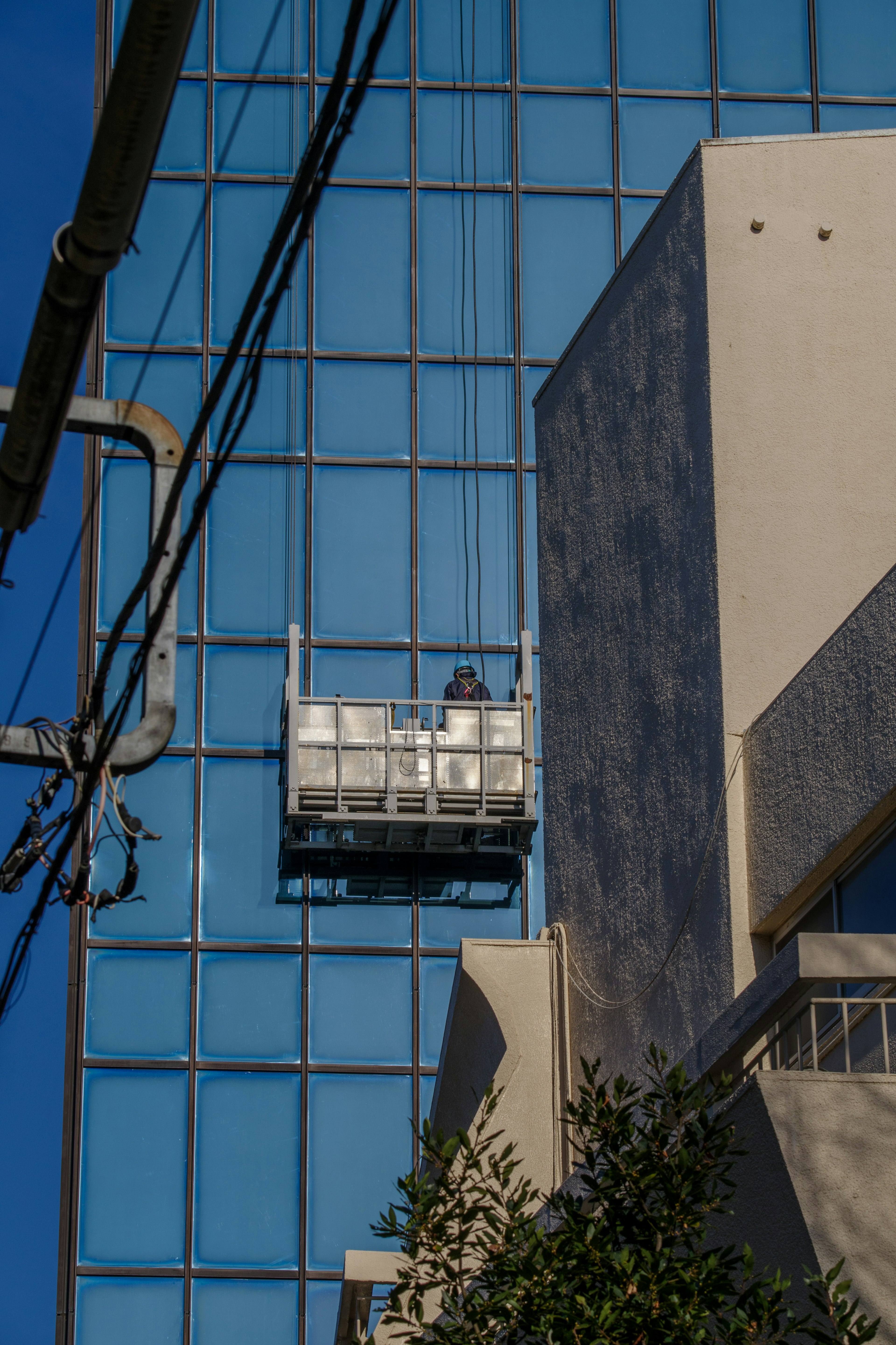 A person working on the exterior of a blue glass building