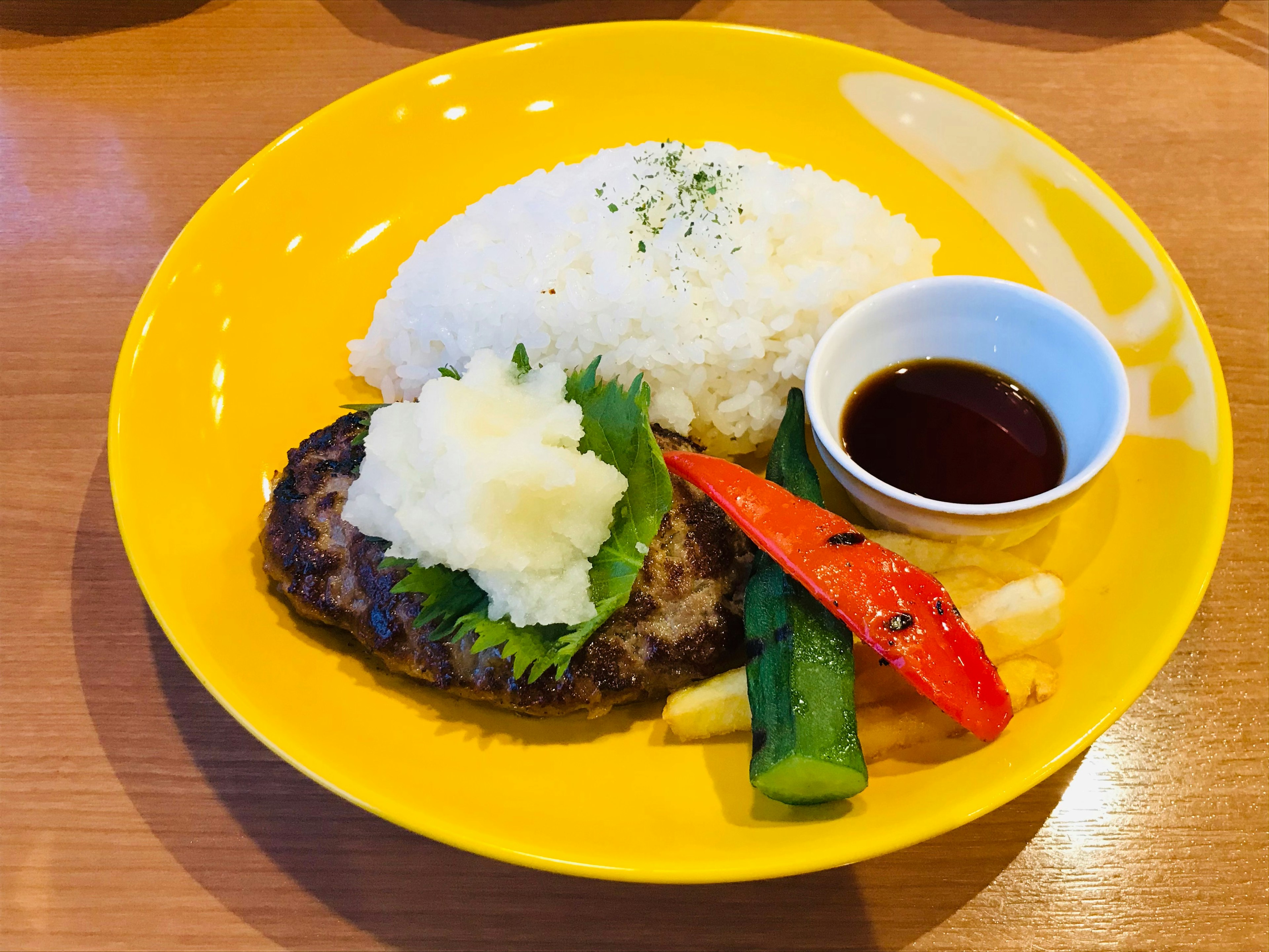 Hidangan dengan nasi dan steak hamburger di piring kuning