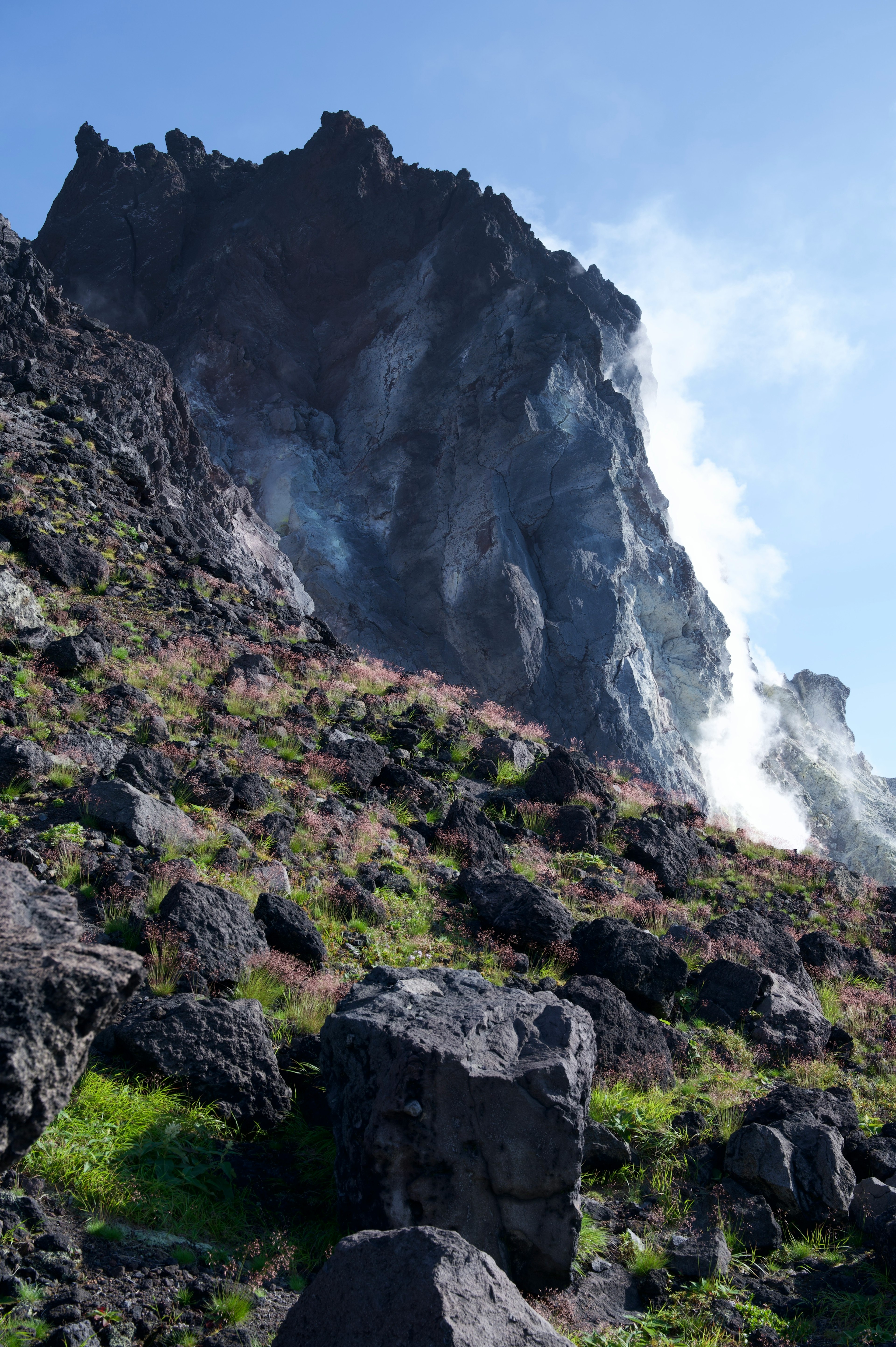 Acantilado volcánico empinado con terreno rocoso y vapor