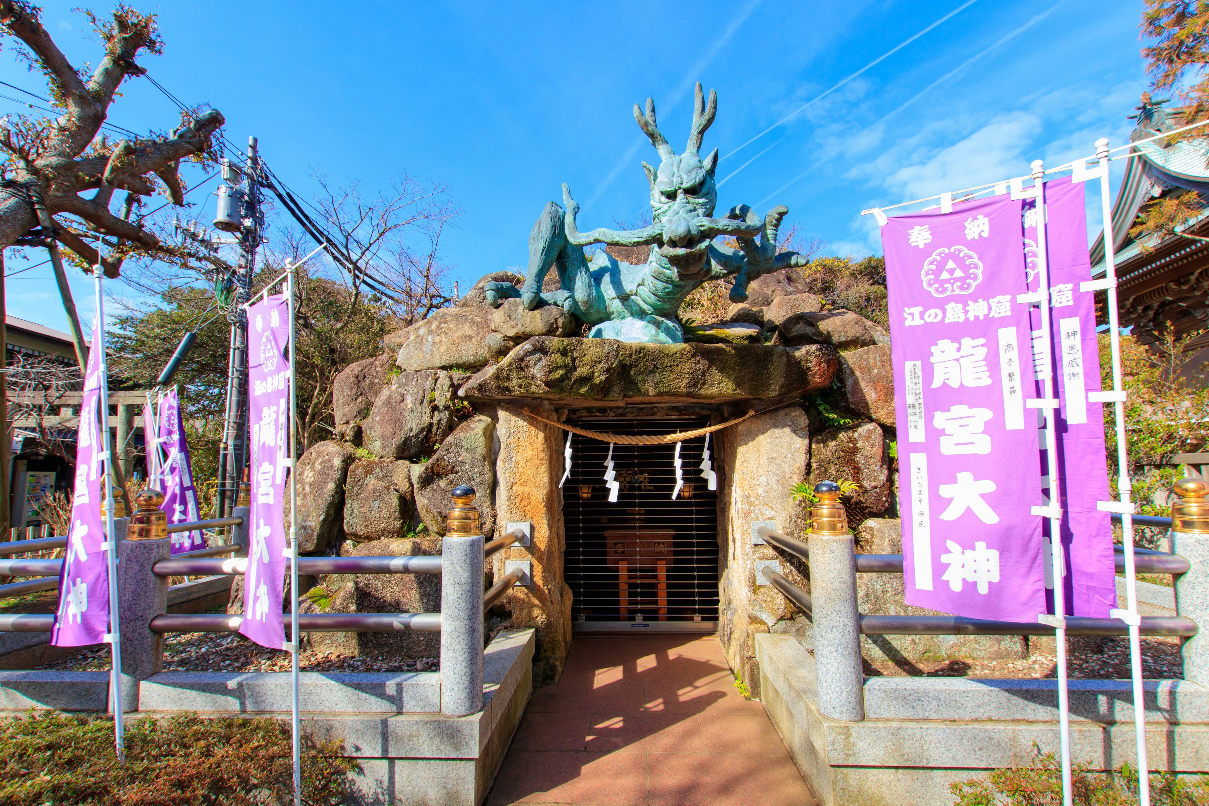 神社の入り口にある青銅のドラゴン像と紫の旗