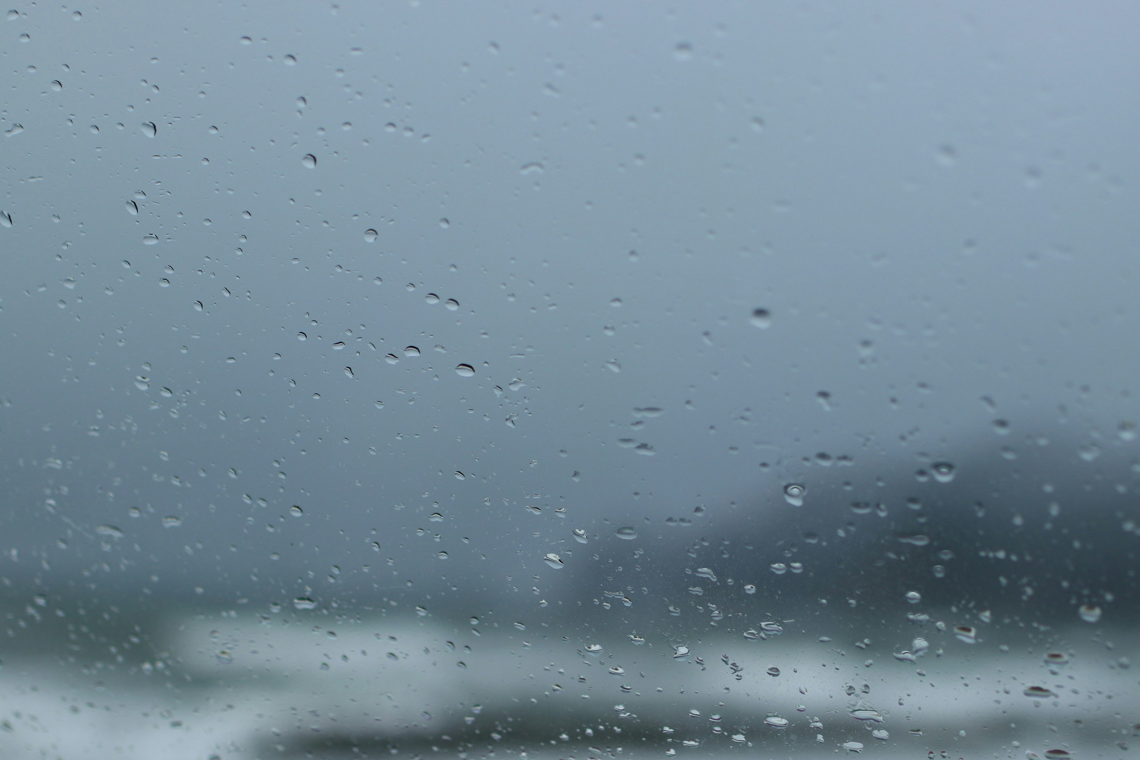 雨滴のついた窓越しの青い海の風景