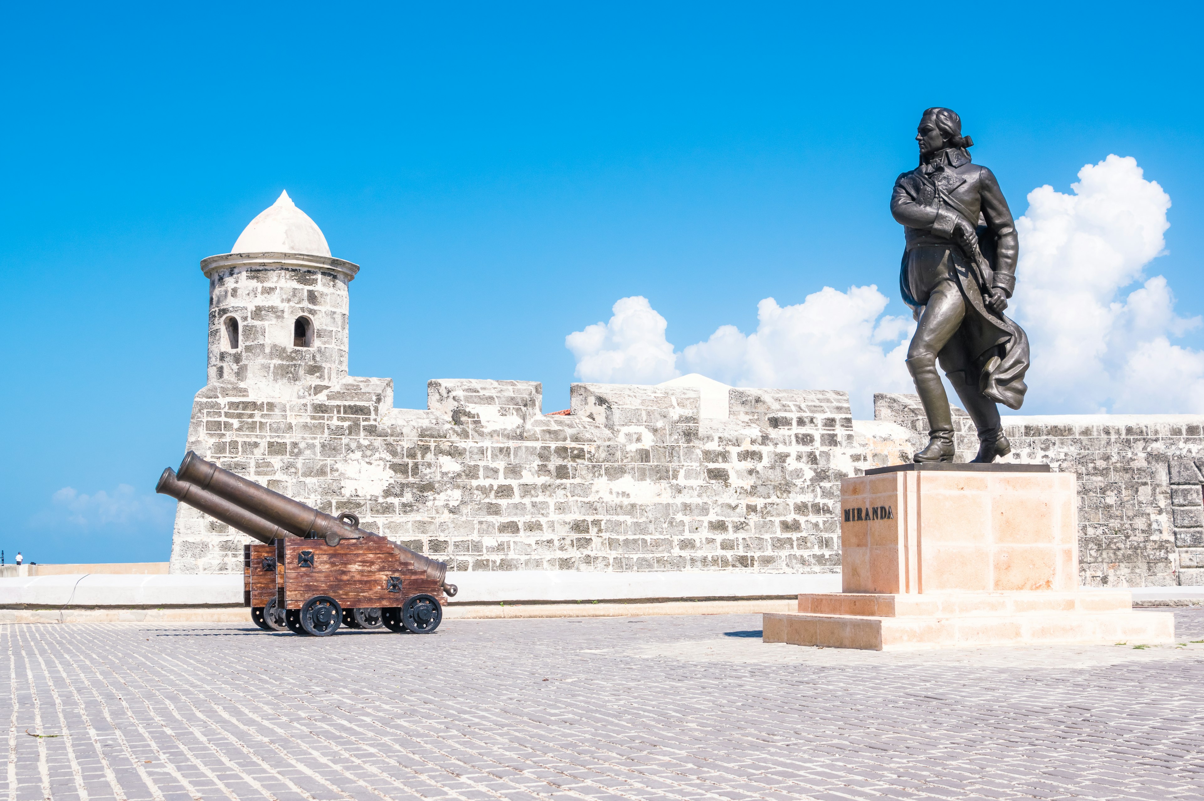 Forteresse historique avec un canon et une statue sous un ciel bleu