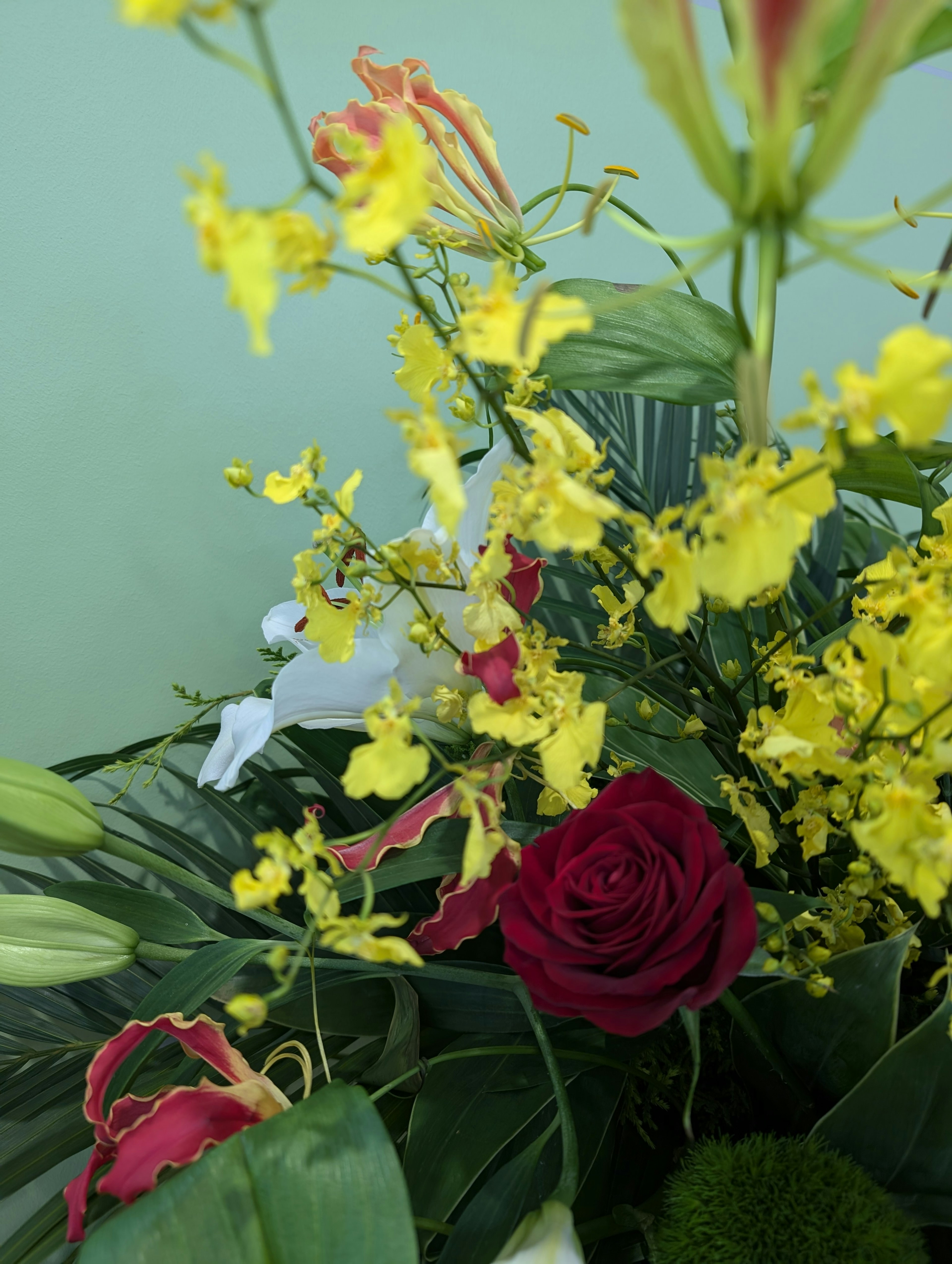 色とりどりの花々が生けられたアレンジメント 背景は緑色