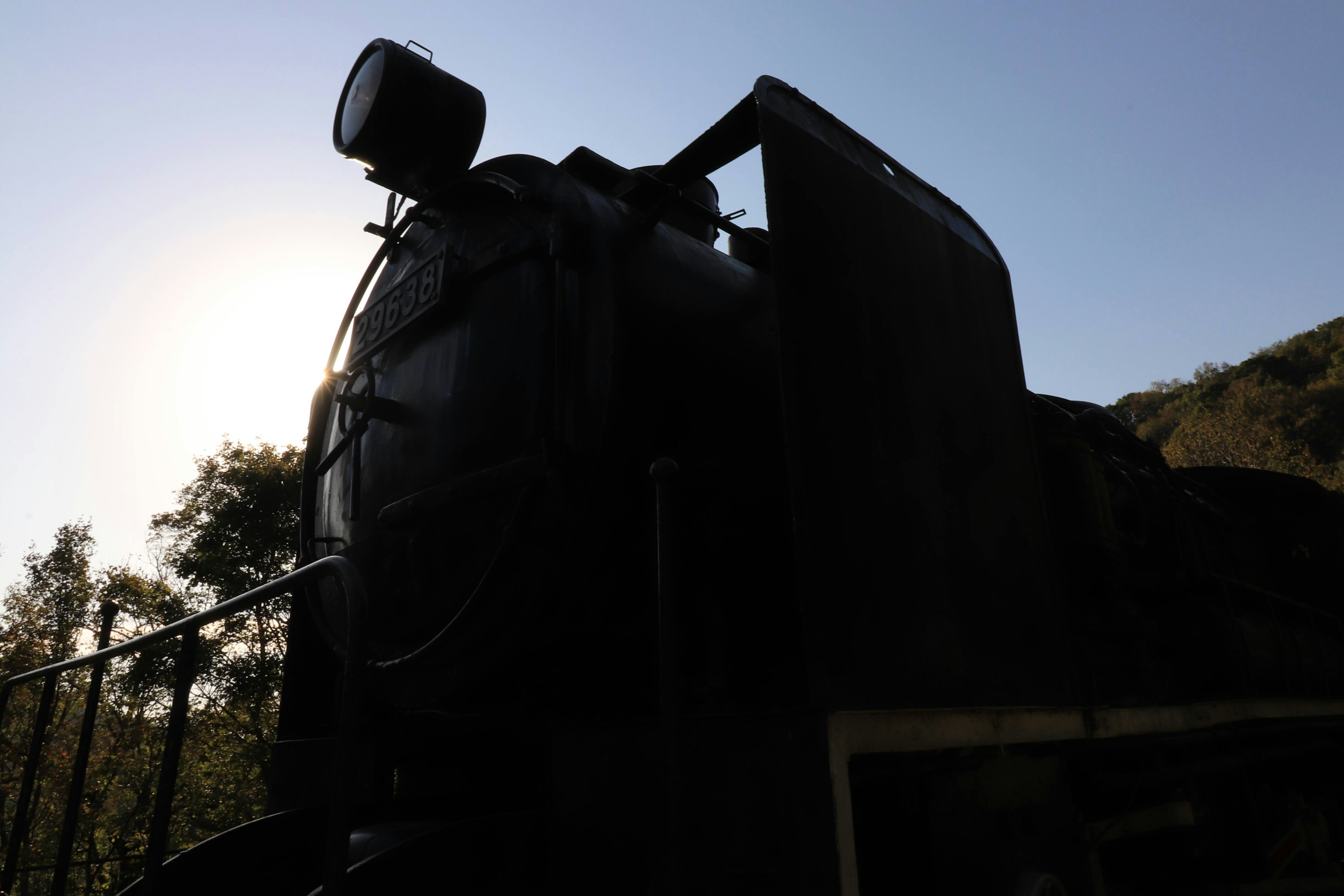 Silhouette di una locomotiva a vapore contro la luce del sole