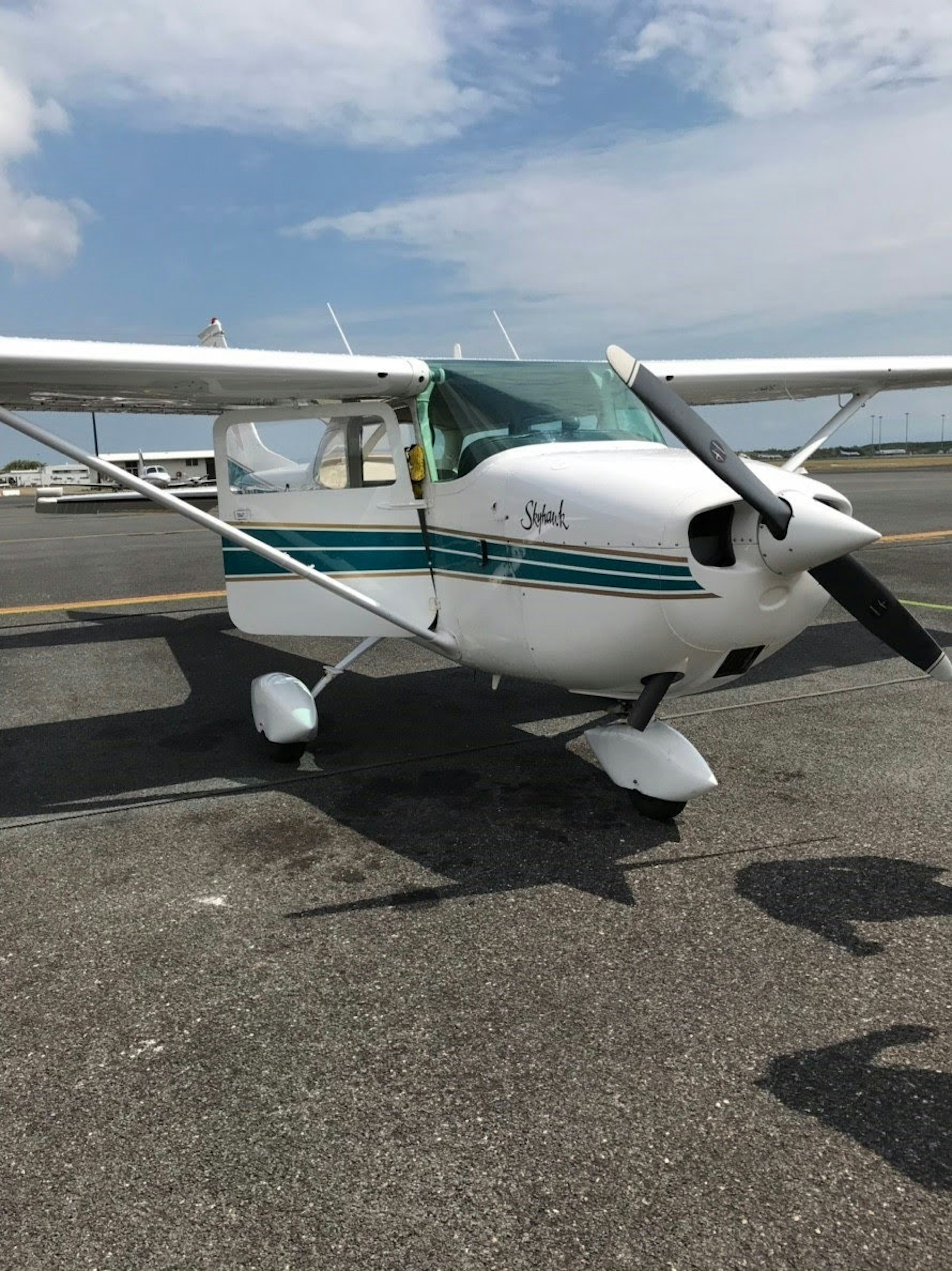 白い小型飛行機が滑走路に停まっている