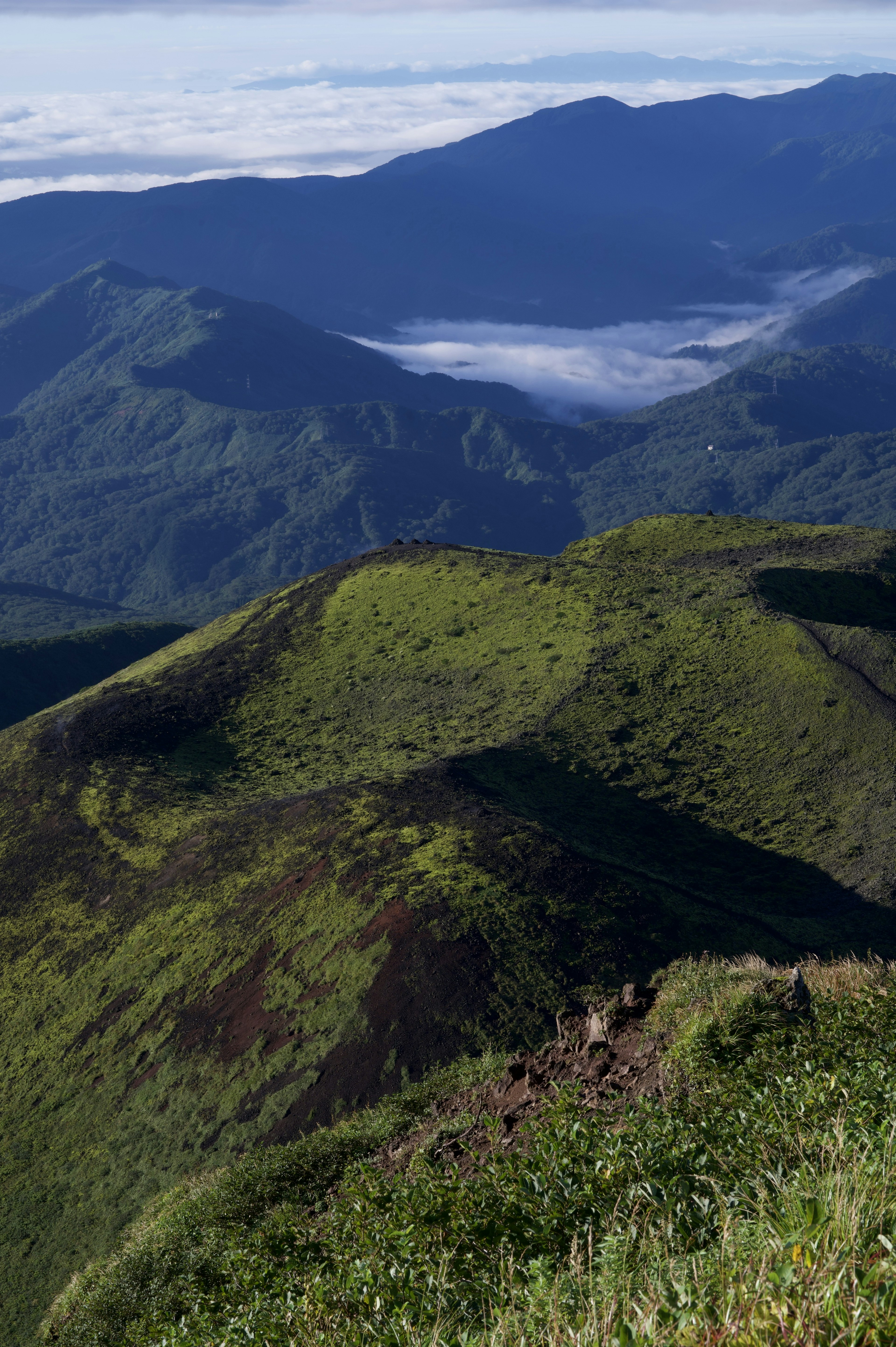 Montagnes verdoyantes avec des collines ondulantes et une vue sur les nuages