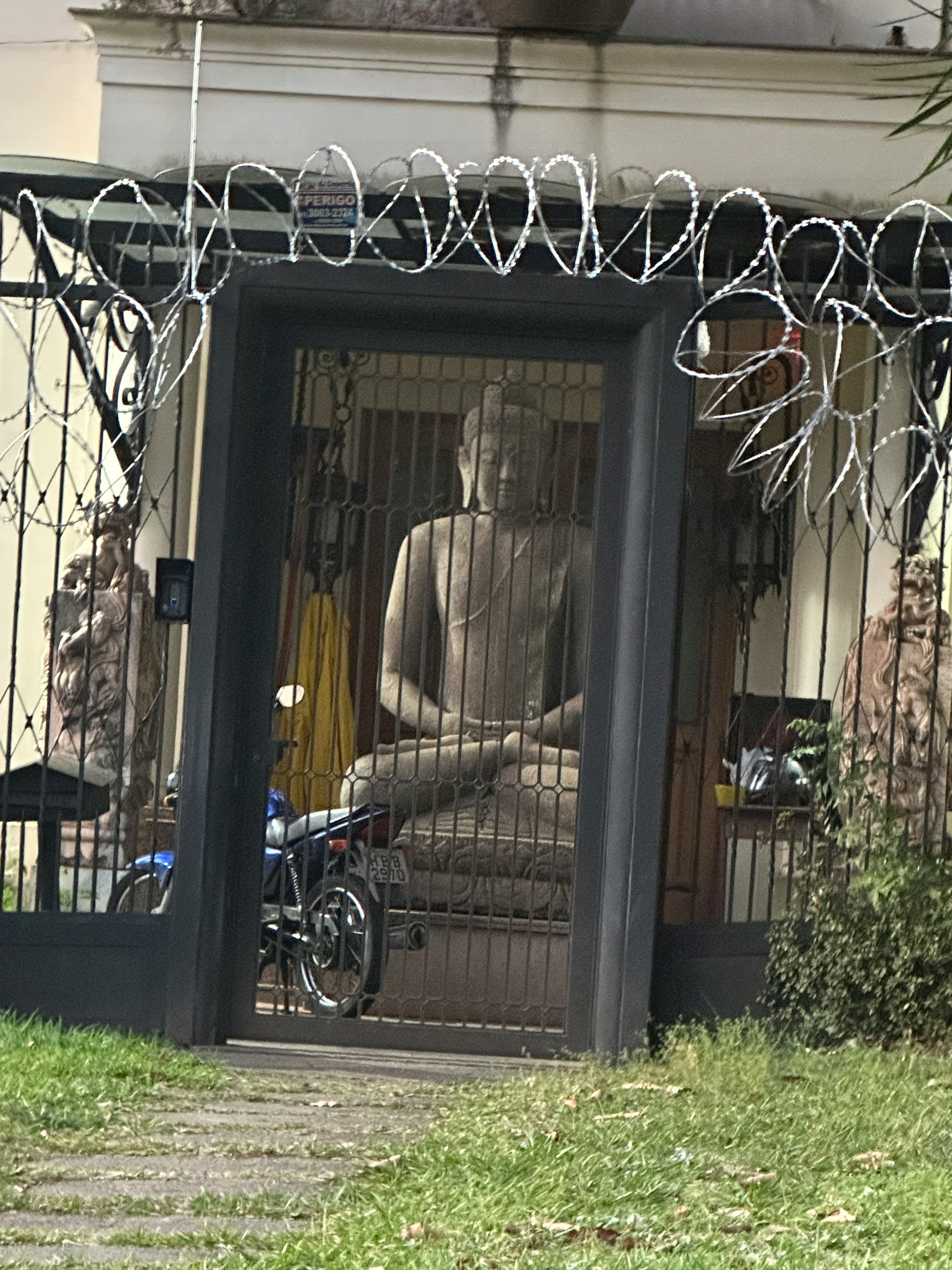 Eine große Buddha-Statue, die durch einen eingezäunten Garten sichtbar ist