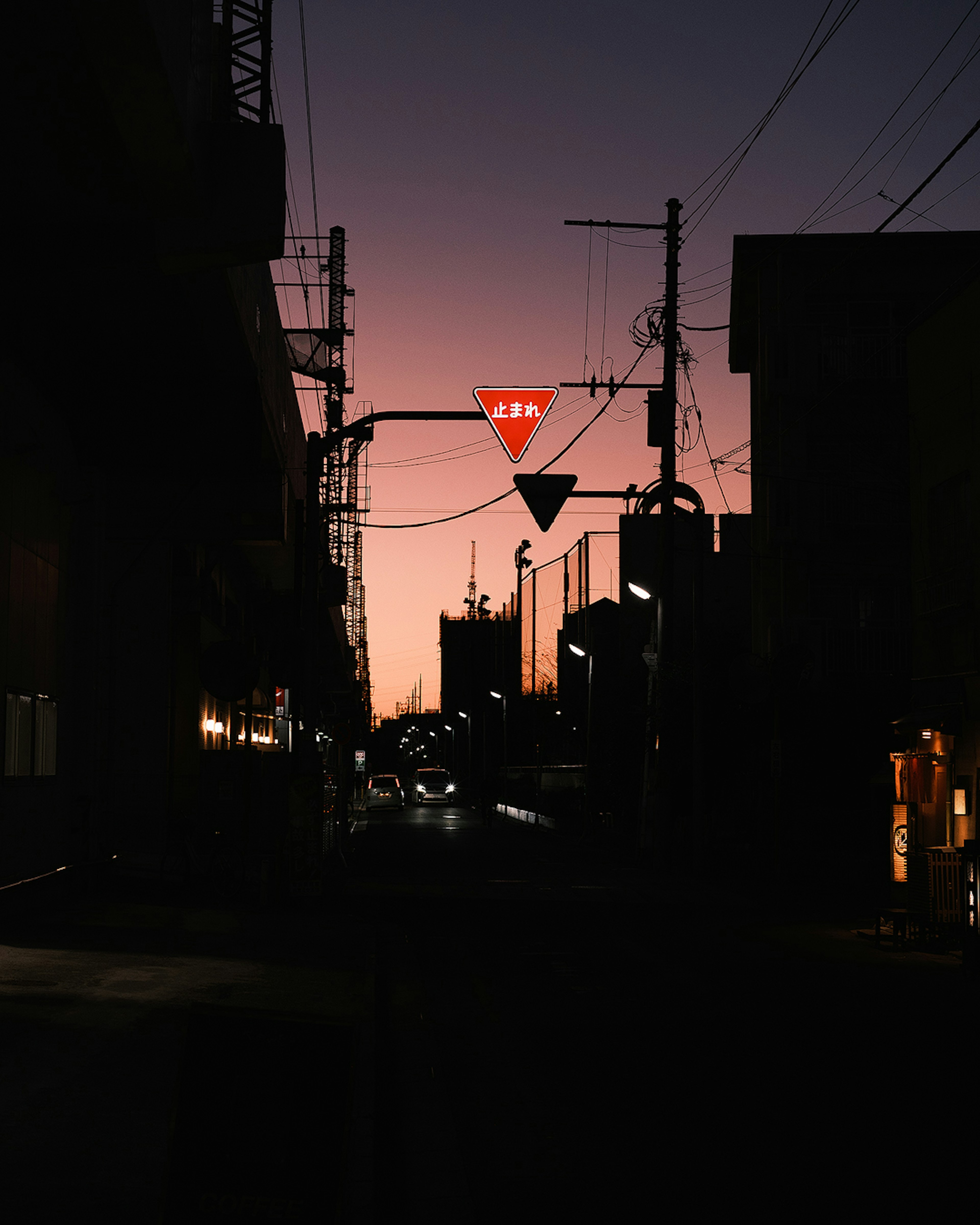 Silhouette di una strada di città al crepuscolo con un segnale di dare precedenza