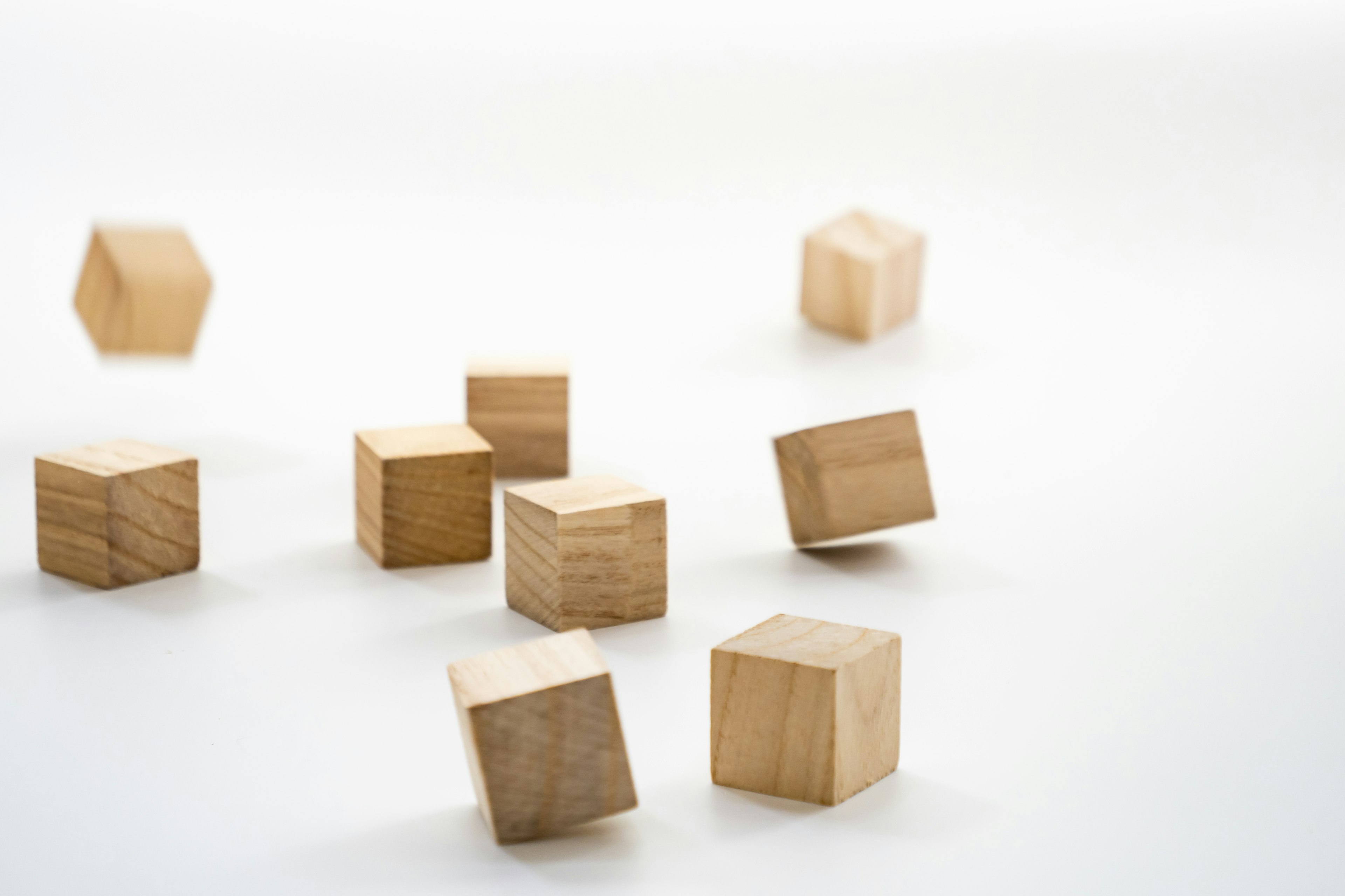 Wooden cubes and hexagonal blocks scattered on a white background