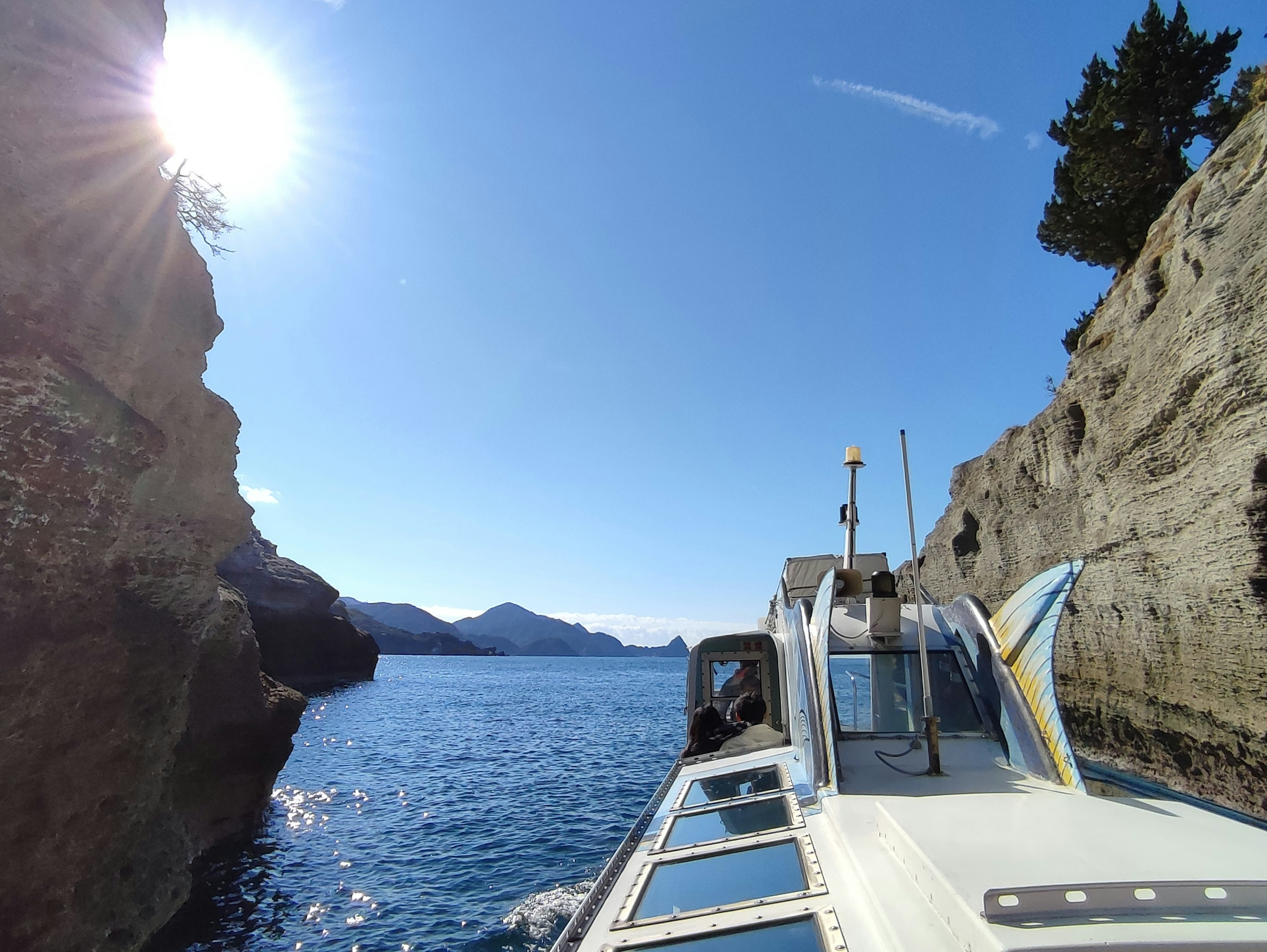 Bateau naviguant entre des falaises sous un soleil radieux