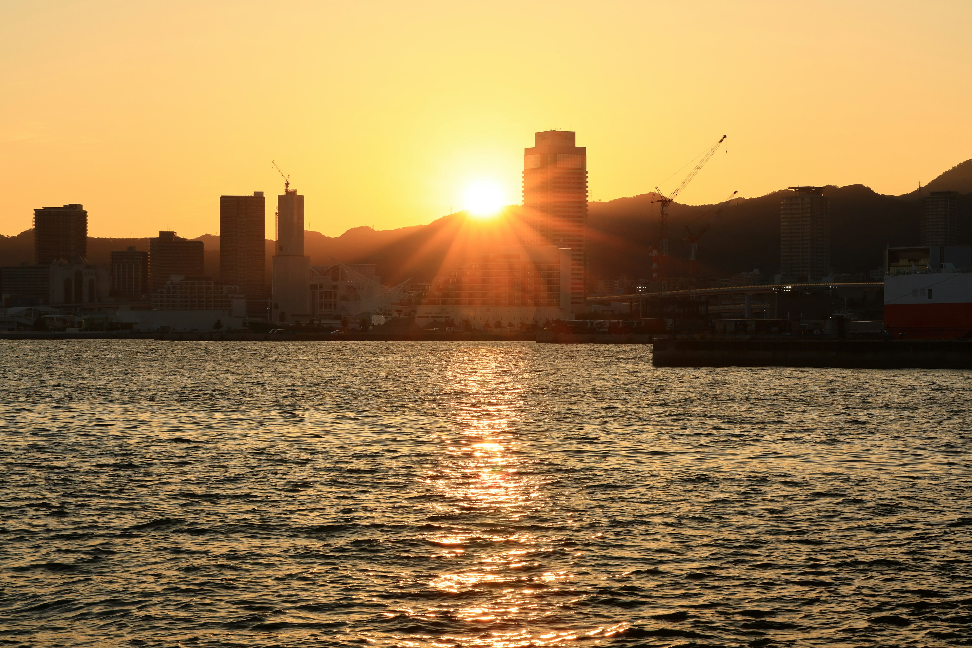 Paisaje urbano al atardecer con el sol reflejándose en el agua