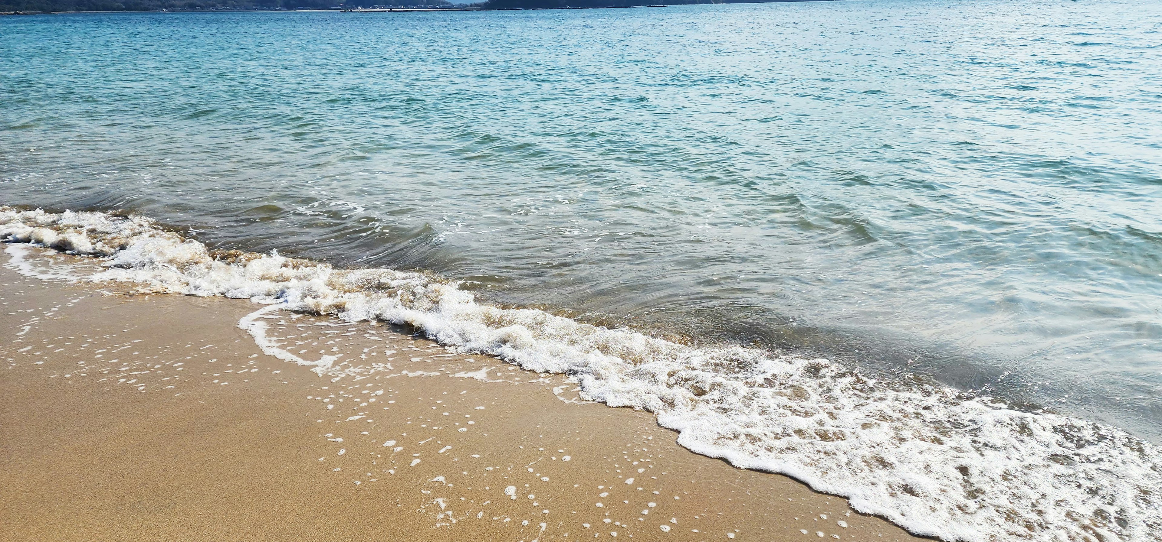 Costa calma con onde che si infrangono sulla spiaggia di sabbia