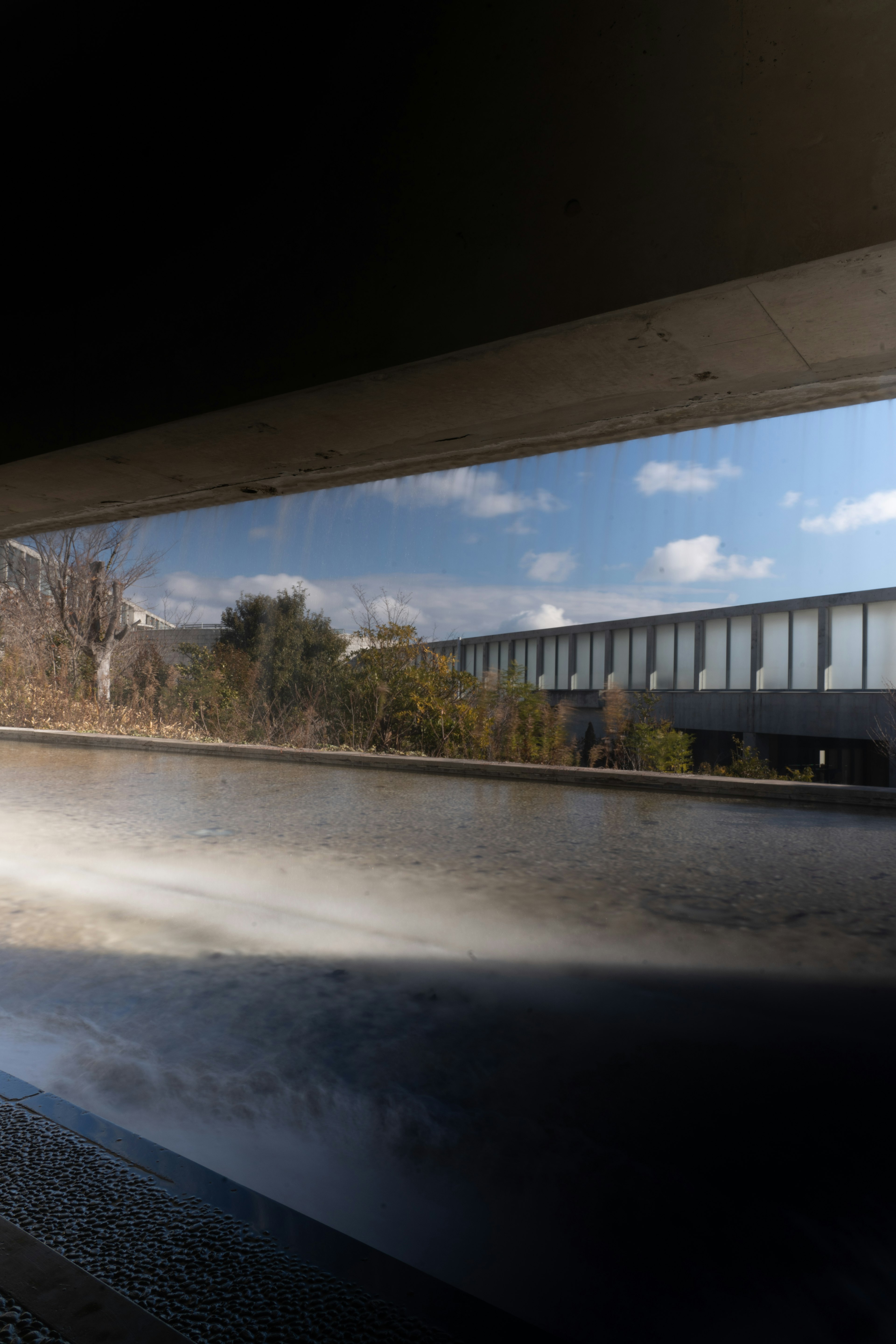 Vista del cielo azul y del paisaje verde a través de una estructura arquitectónica moderna