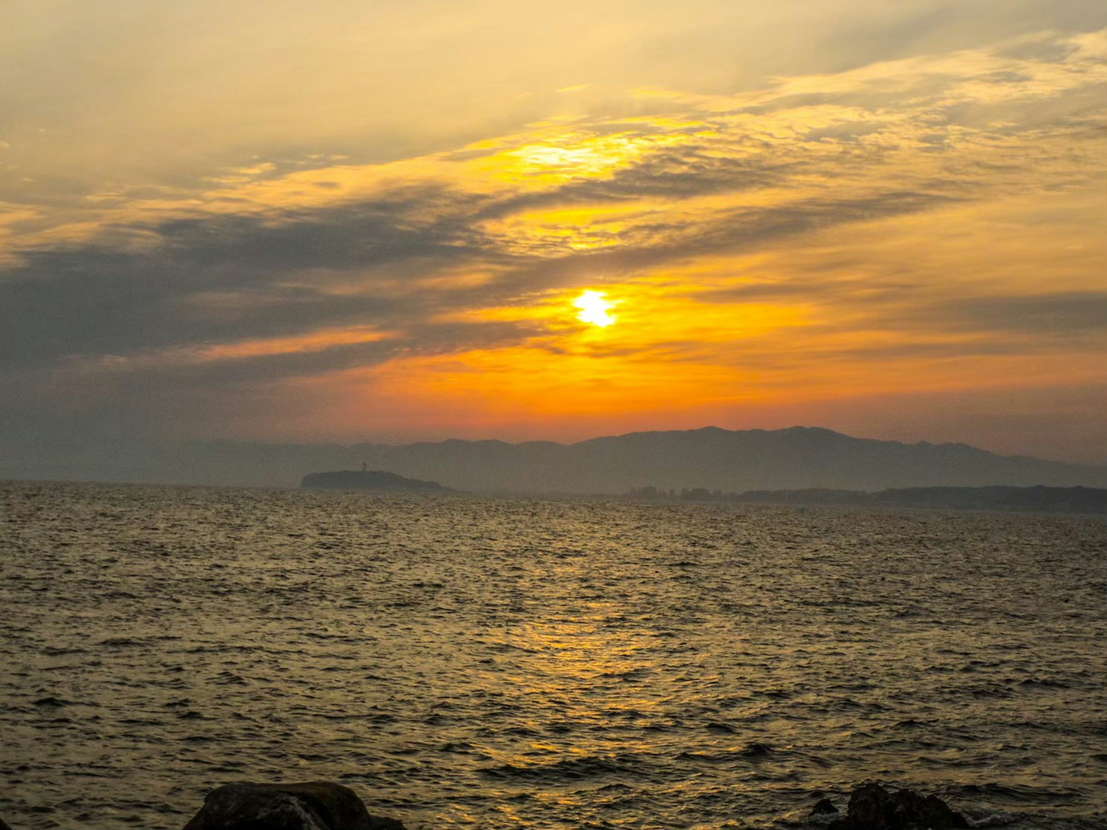 Atardecer sobre el océano con montañas al fondo