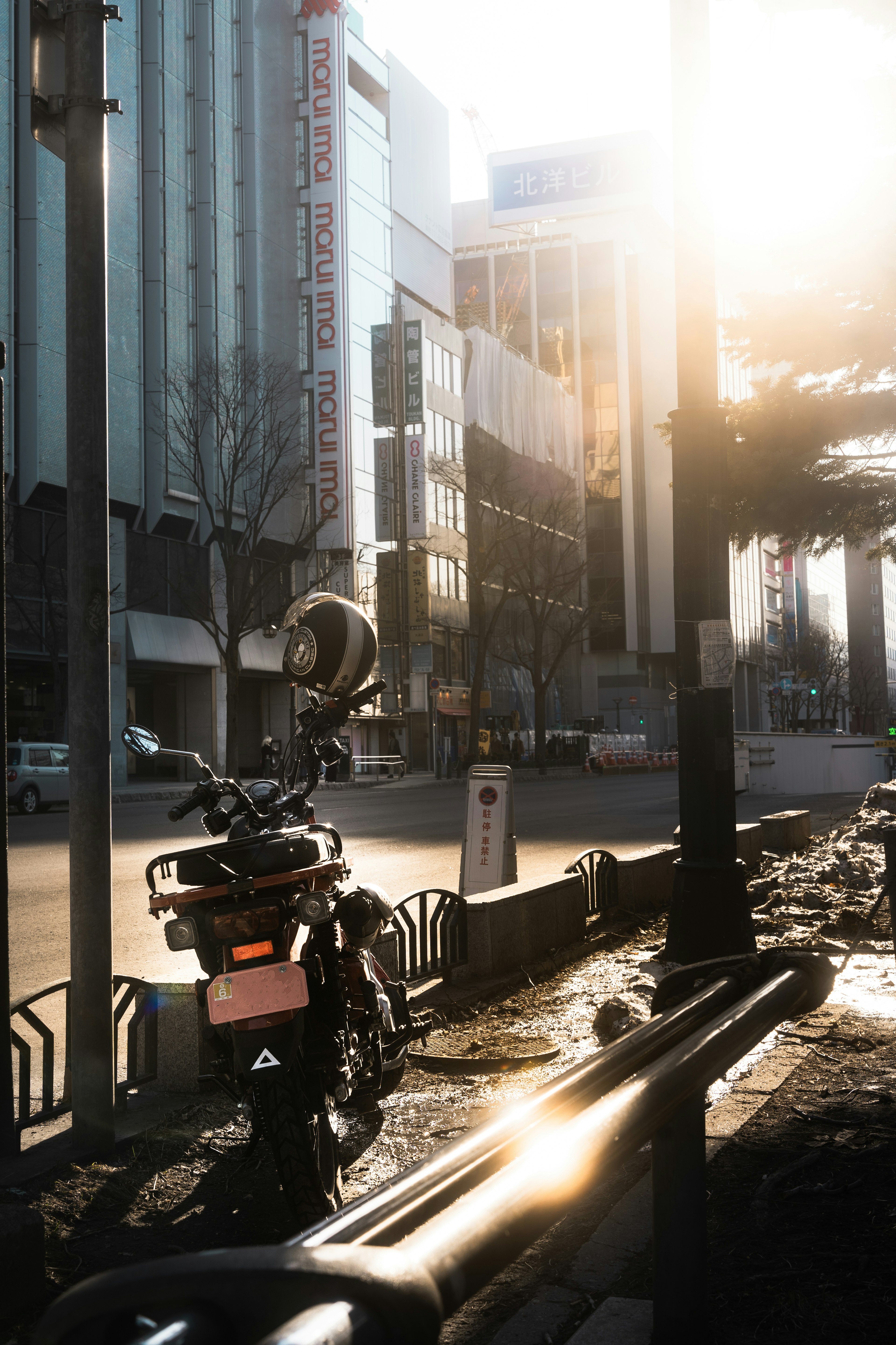 Scène de rue urbaine avec une moto garée et la lumière du soleil