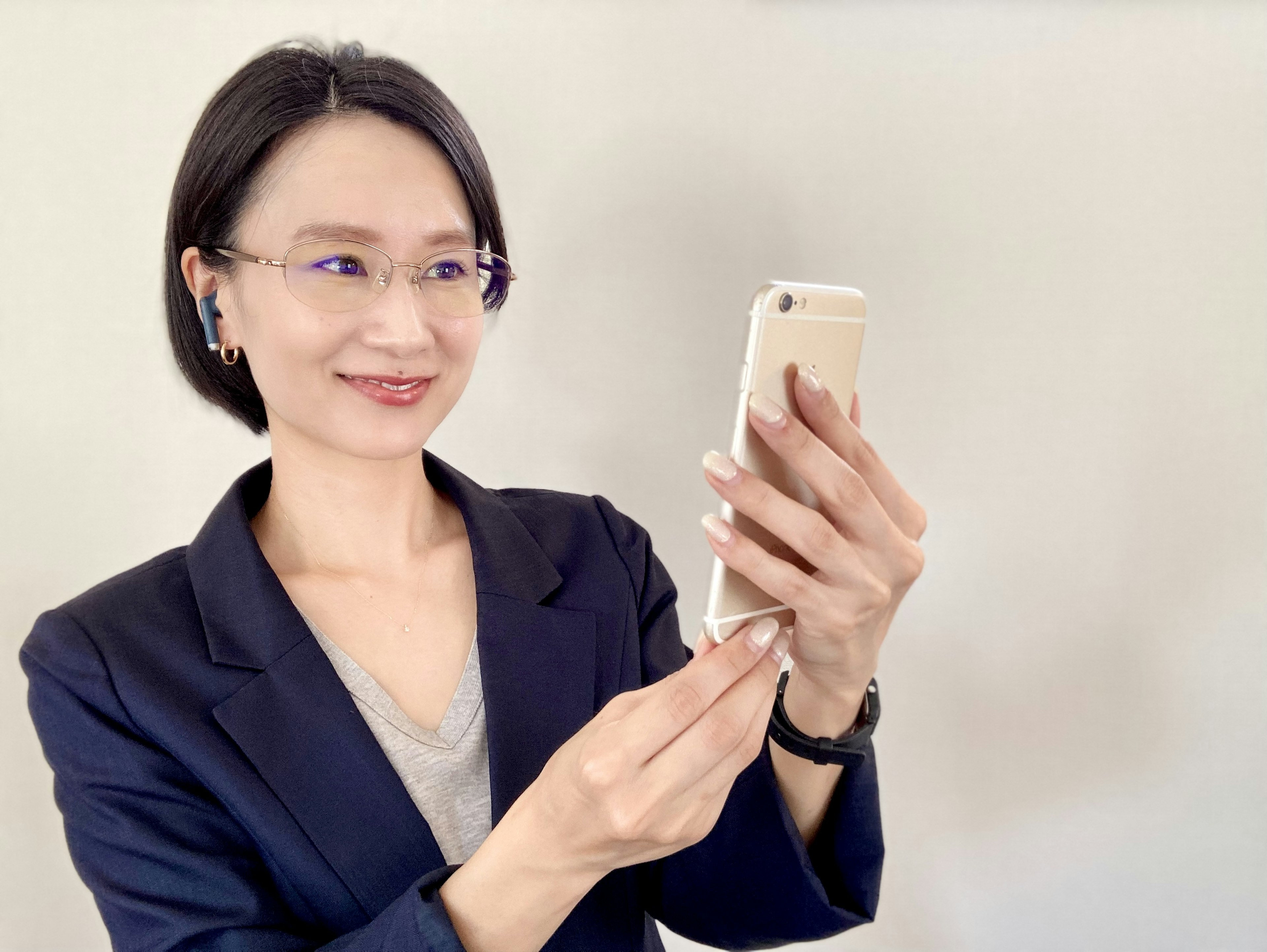 Una mujer sonriendo mientras sostiene un teléfono inteligente con atuendo de negocios