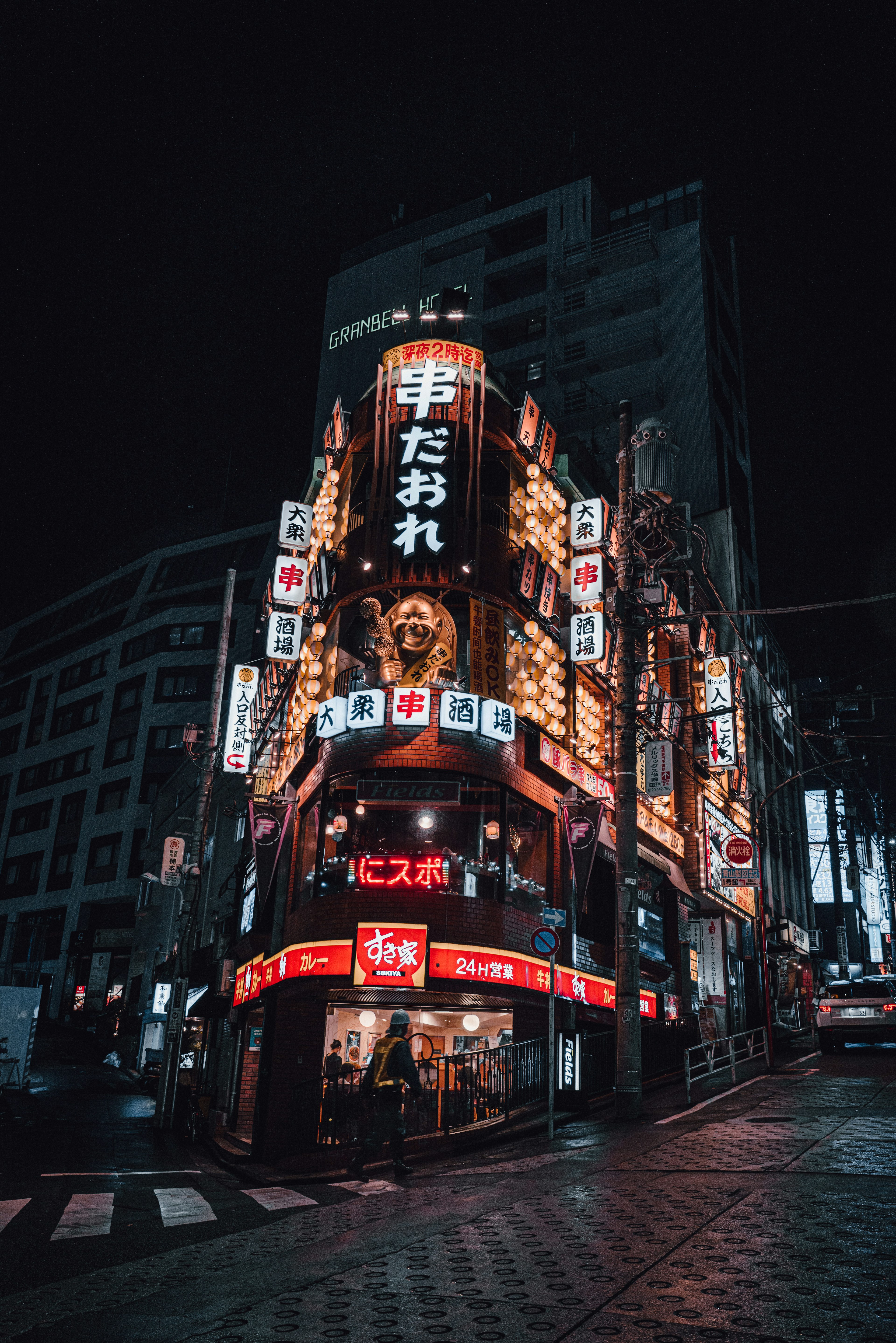 夜の街角に立つ明るい看板の居酒屋