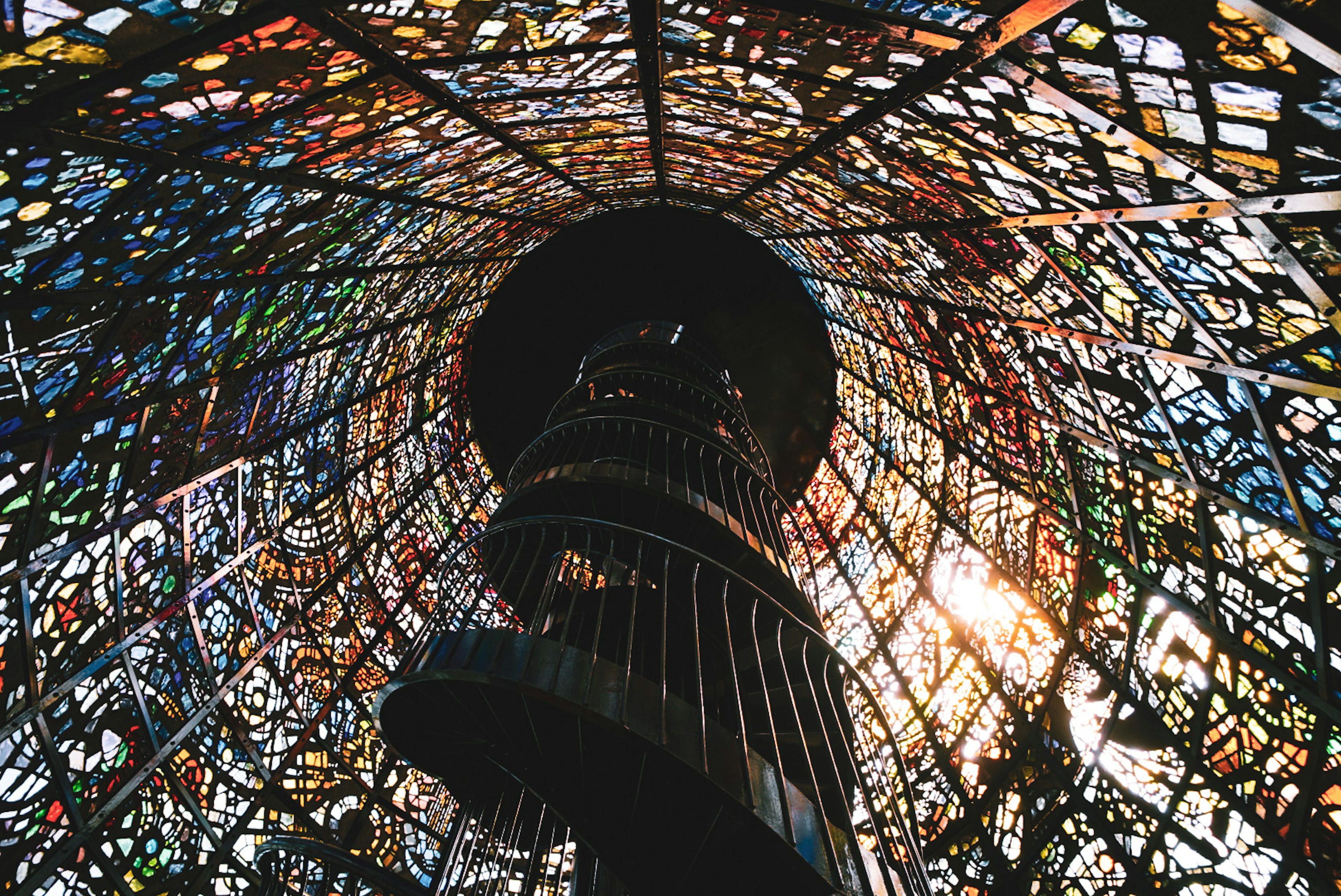 View of a spiral staircase surrounded by colorful stained glass