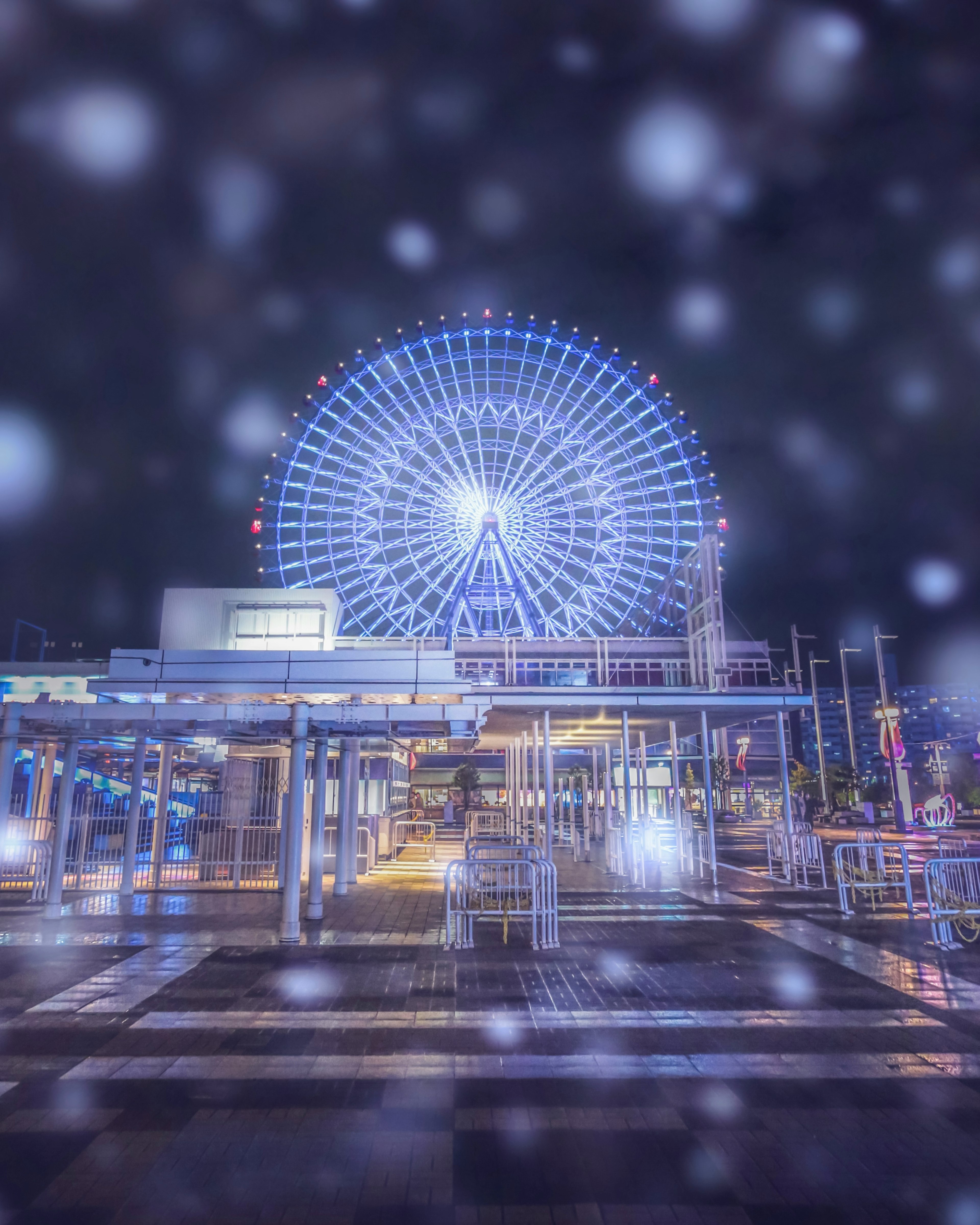 Beleuchtetes Riesenrad bei Nacht umgeben von fallendem Schnee