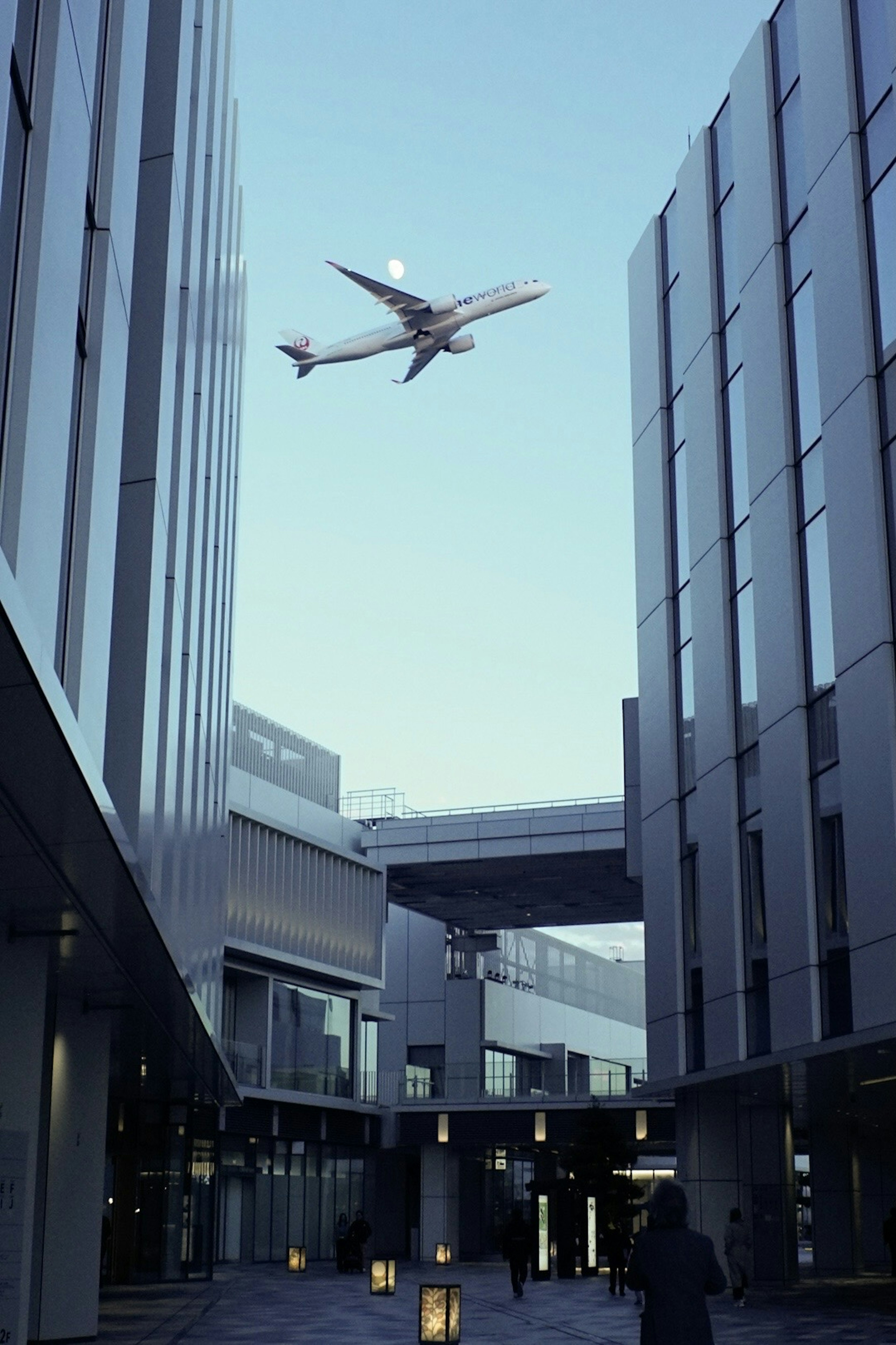 高層ビルの間を飛行機が飛ぶ風景