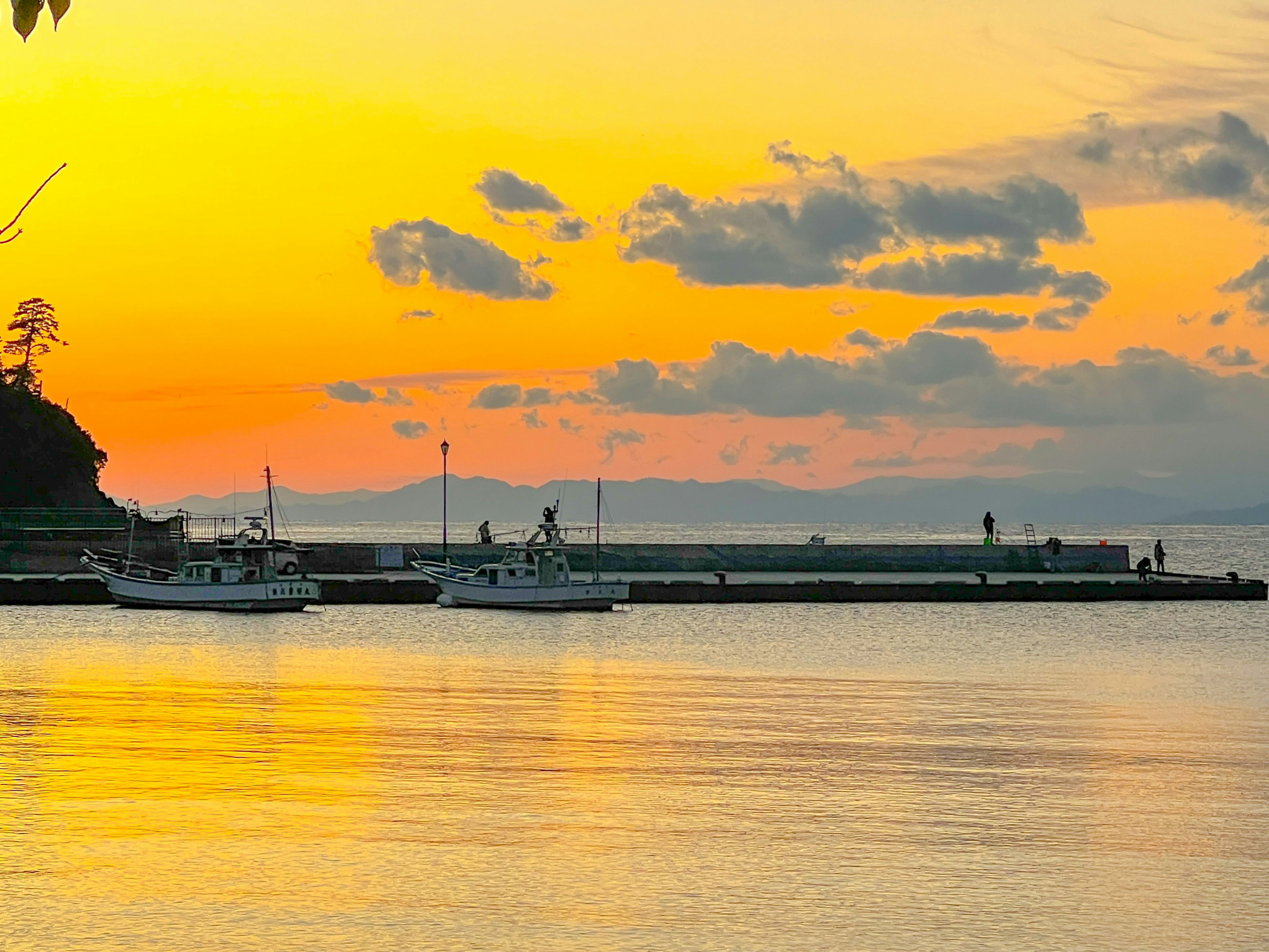 Fishing boats docked at a coastal sunset with calm waters