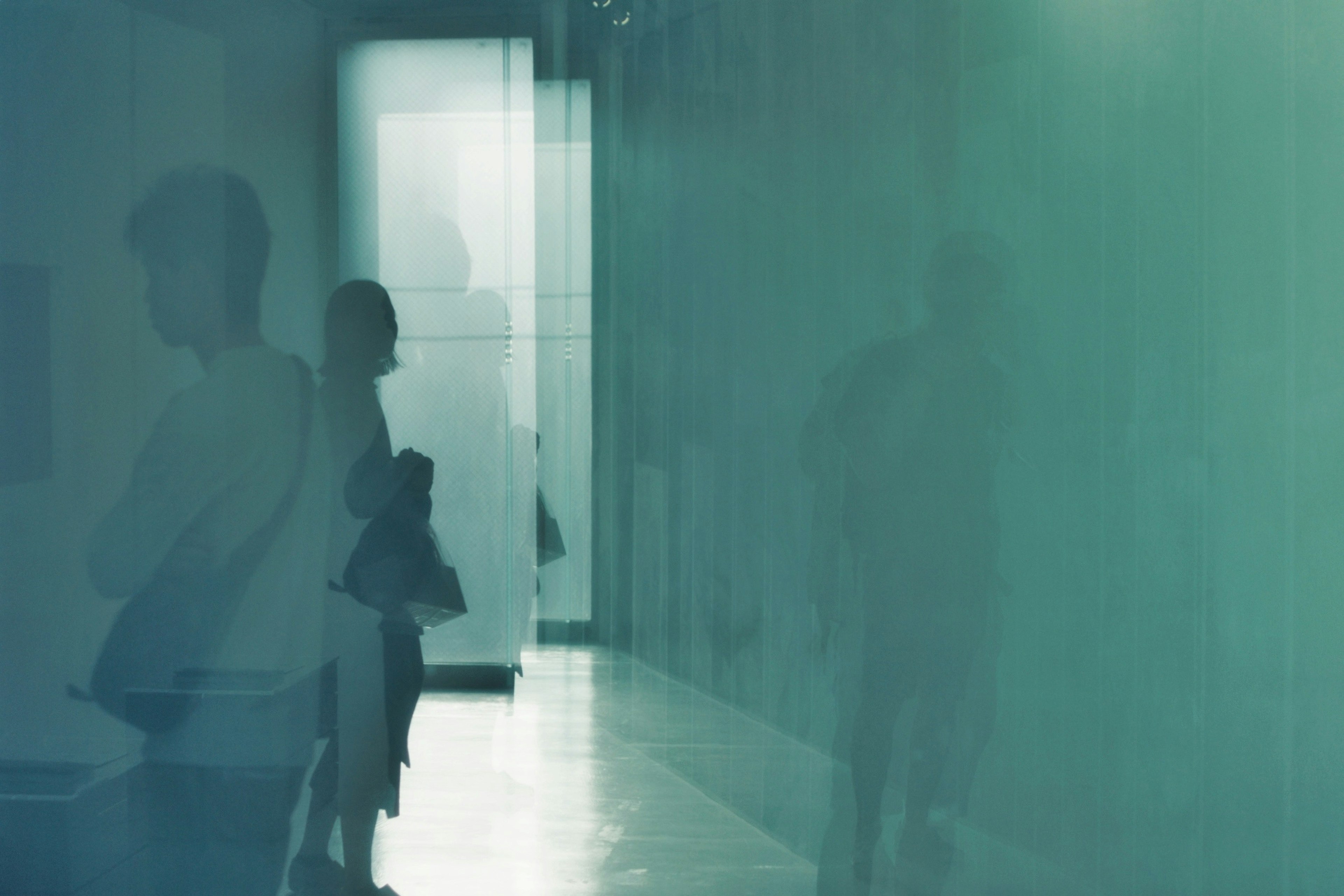 A hallway scene with silhouettes of people against a bluish background